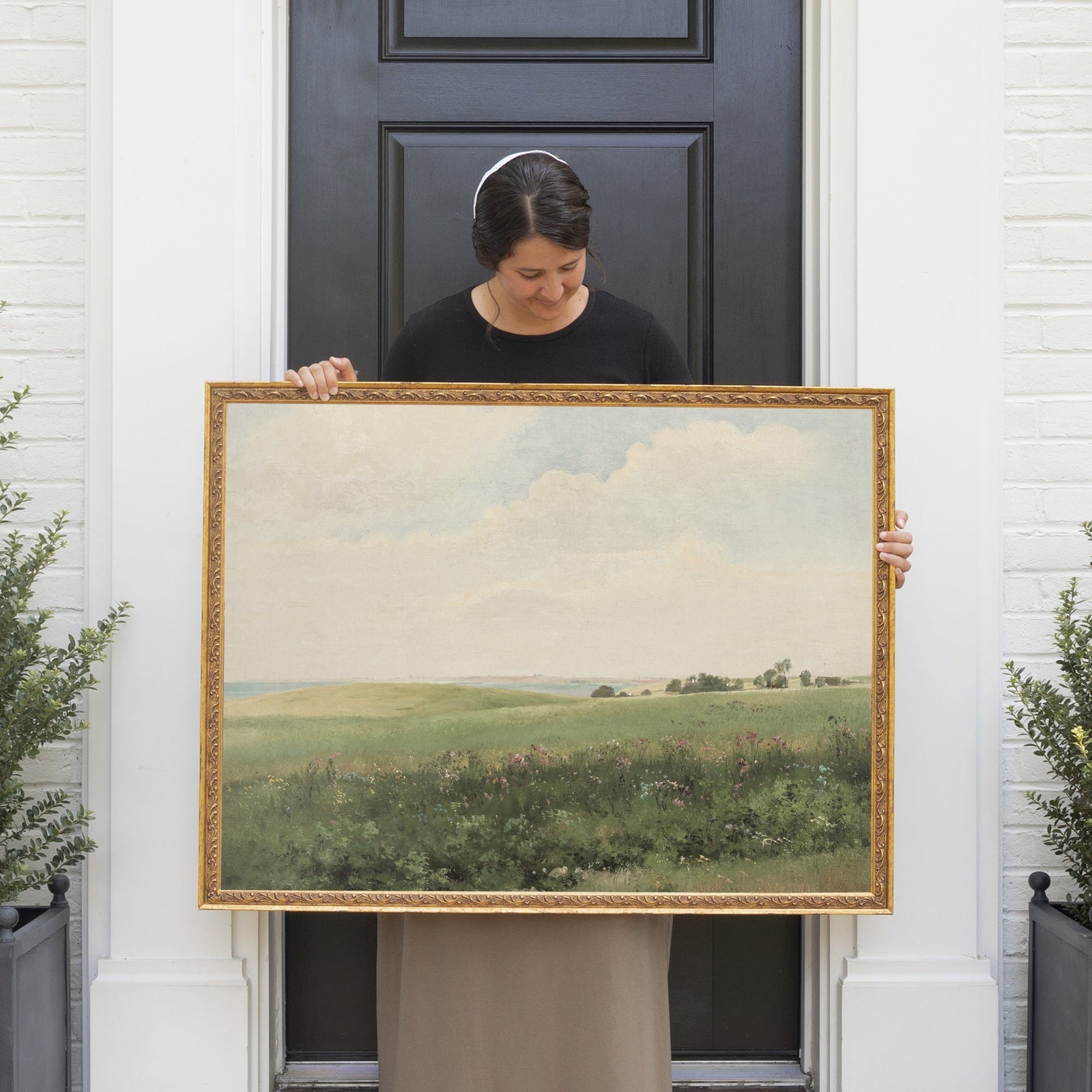 Modern farmhouse living space featuring a plush white sofa and a curated gallery wall of vintage-style gold-framed artwork. Perfect inspiration for rustic and classic home decor enthusiasts.