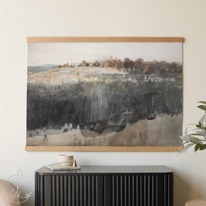 Framed landscape painting on a wall above a black cabinet.