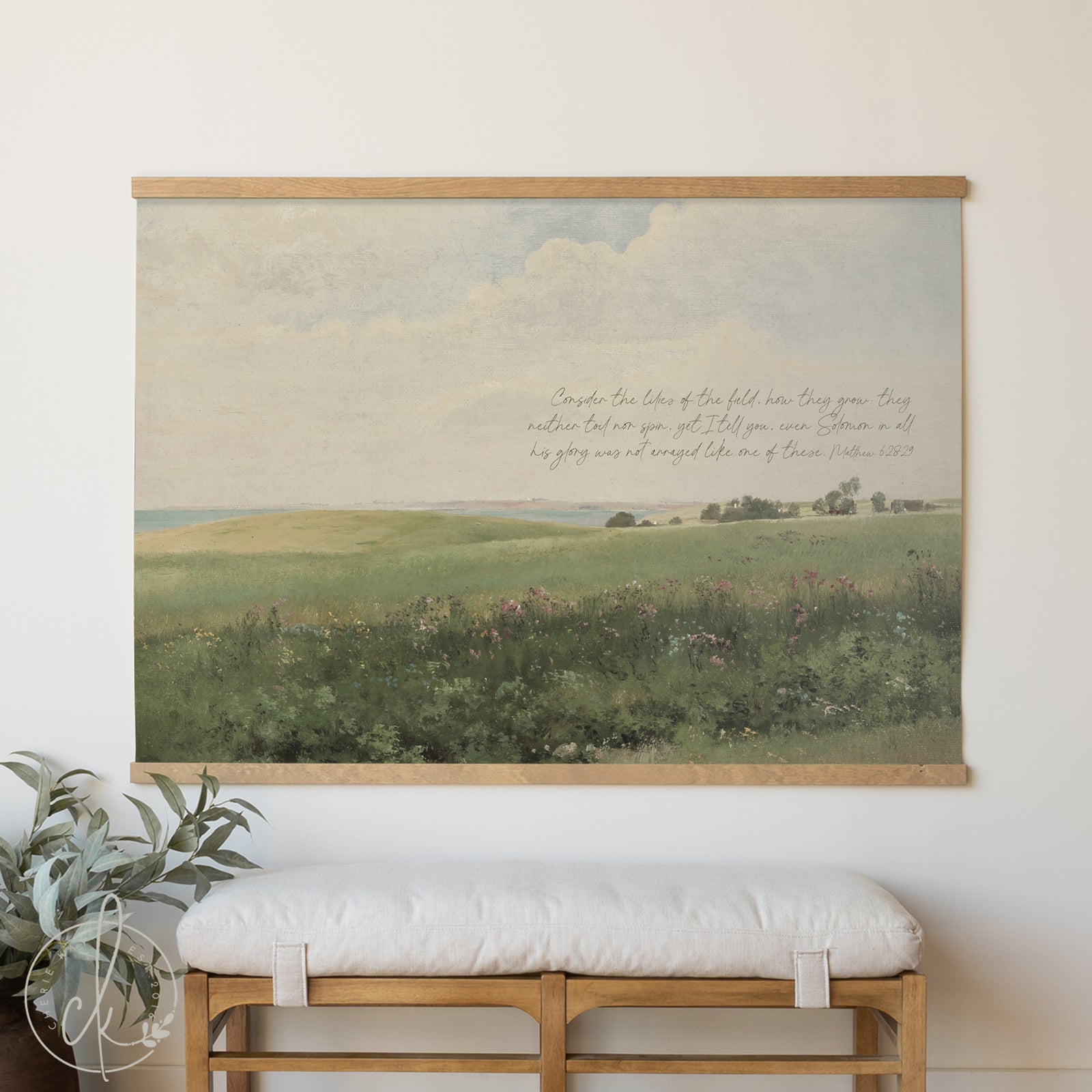 Framed landscape painting with a bench and plant below on a white wall