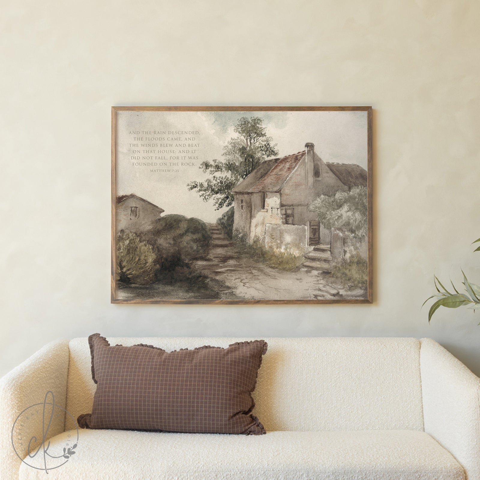 Framed landscape print above a beige sofa with a brown pillow
