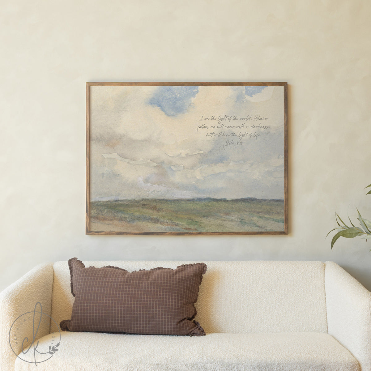 Framed landscape painting above a sofa with a brown pillow