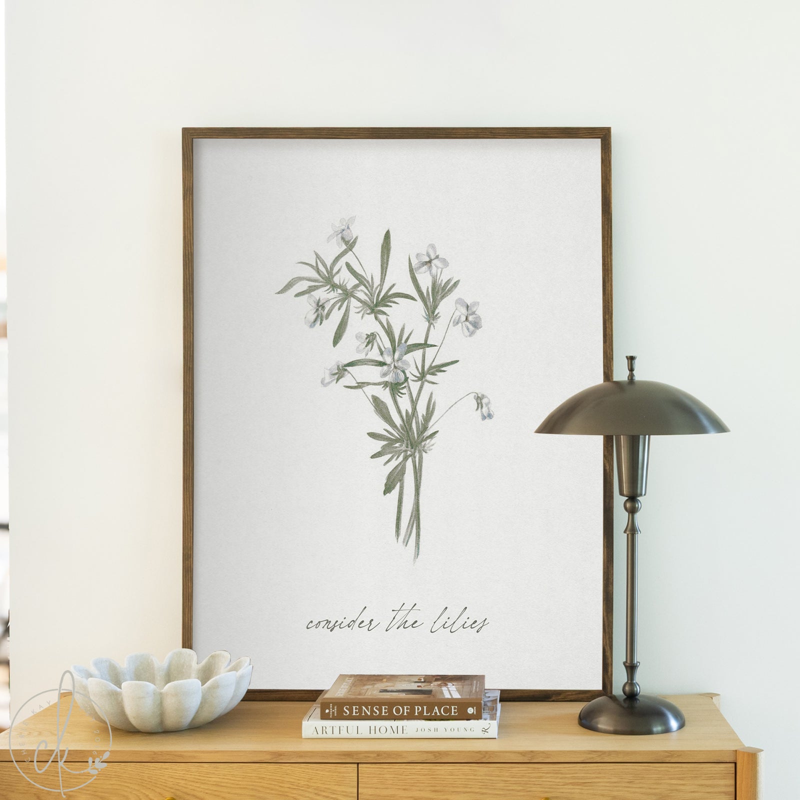 Framed botanical print on a wall above a wooden surface with decor items.