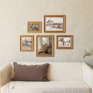 Framed artworks on a wall above a sofa with a decorative pillow.