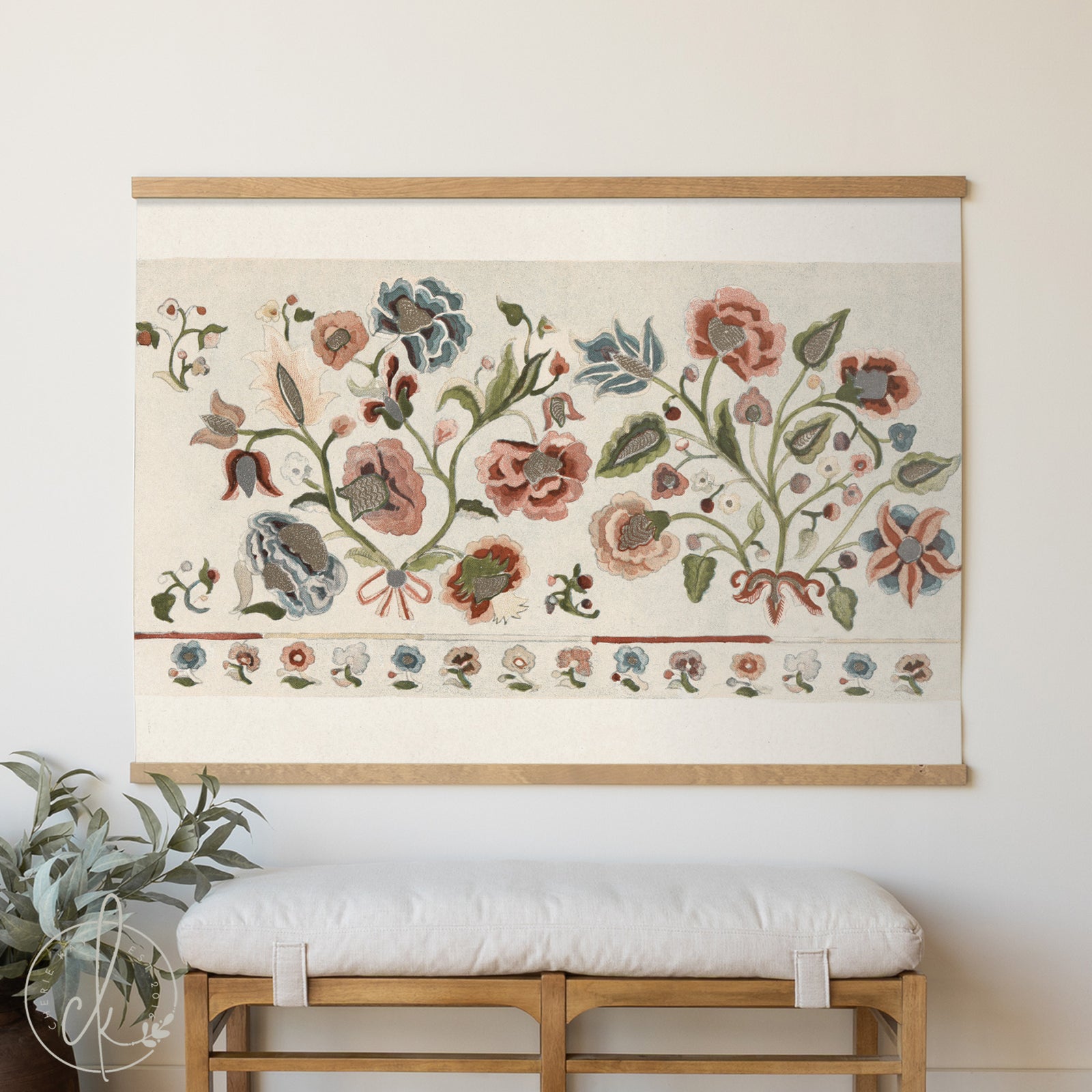 Floral tapestry hanging on a wall above a wooden bench with a white cushion.
