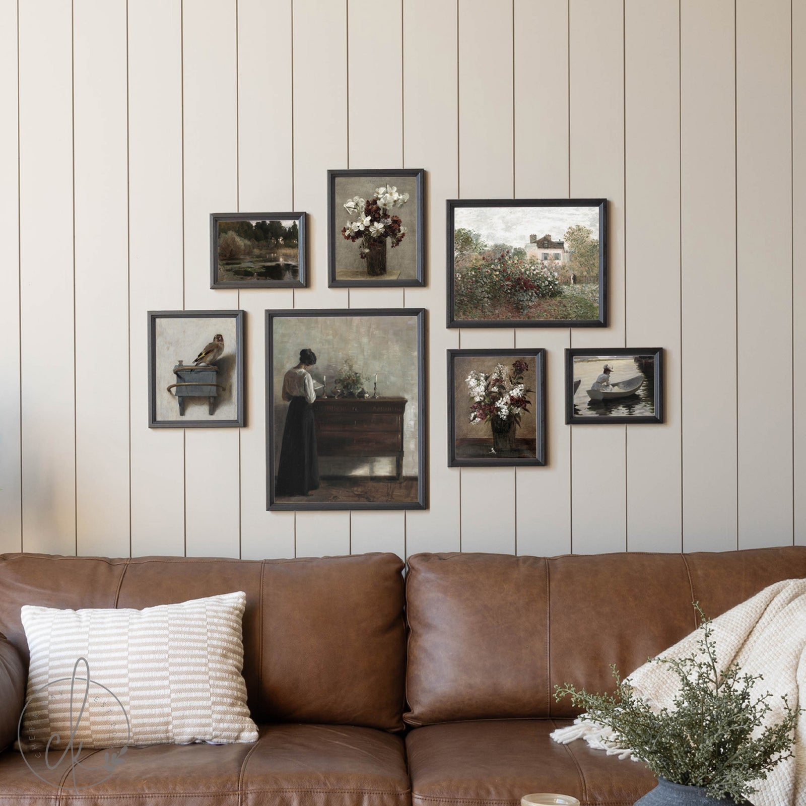 Brown leather sofa with decorative pillows against a wall with framed pictures.