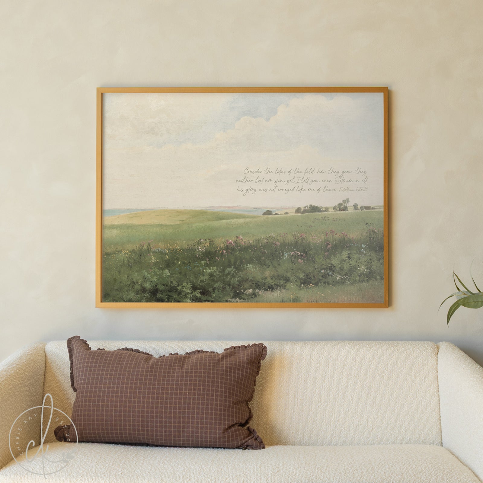 Framed landscape print on a wall above a sofa with a brown pillow.