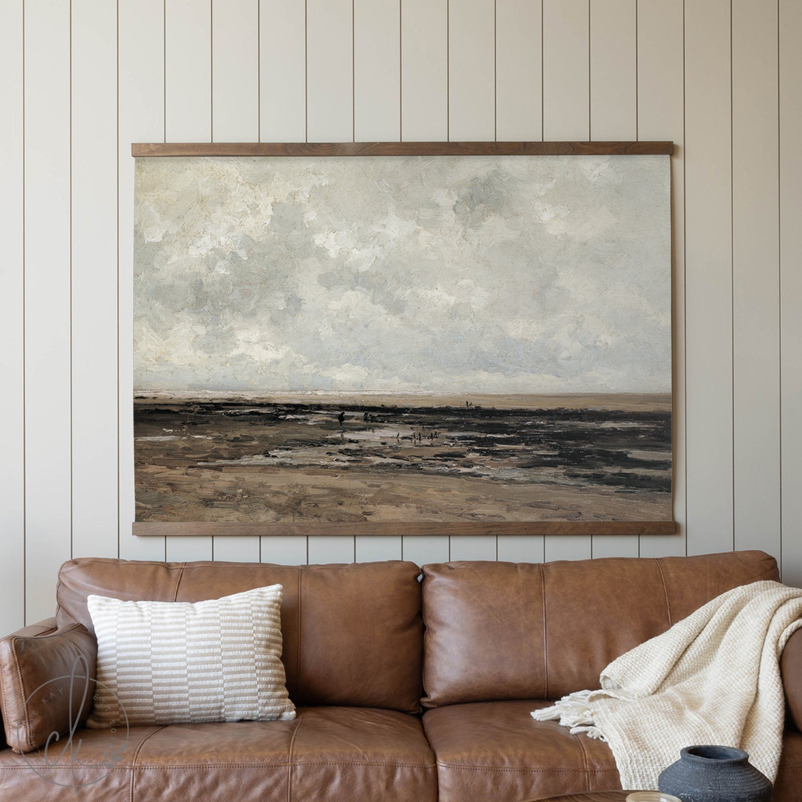 Brown leather sofa with a textured wall art piece in a room with wooden paneling.