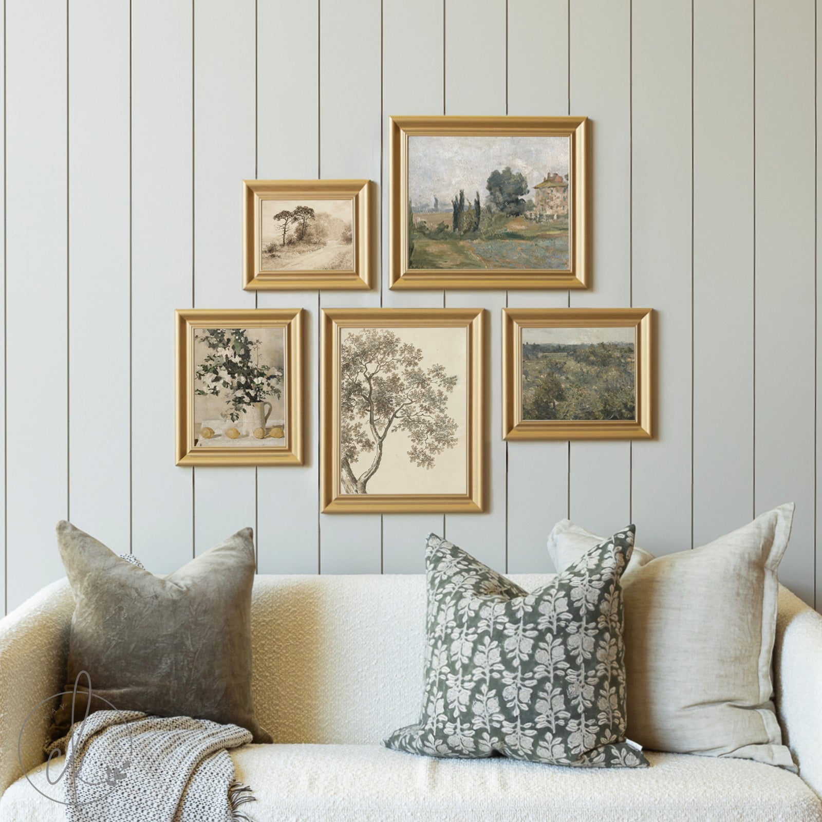 Framed artworks on a wall above a sofa with decorative pillows.