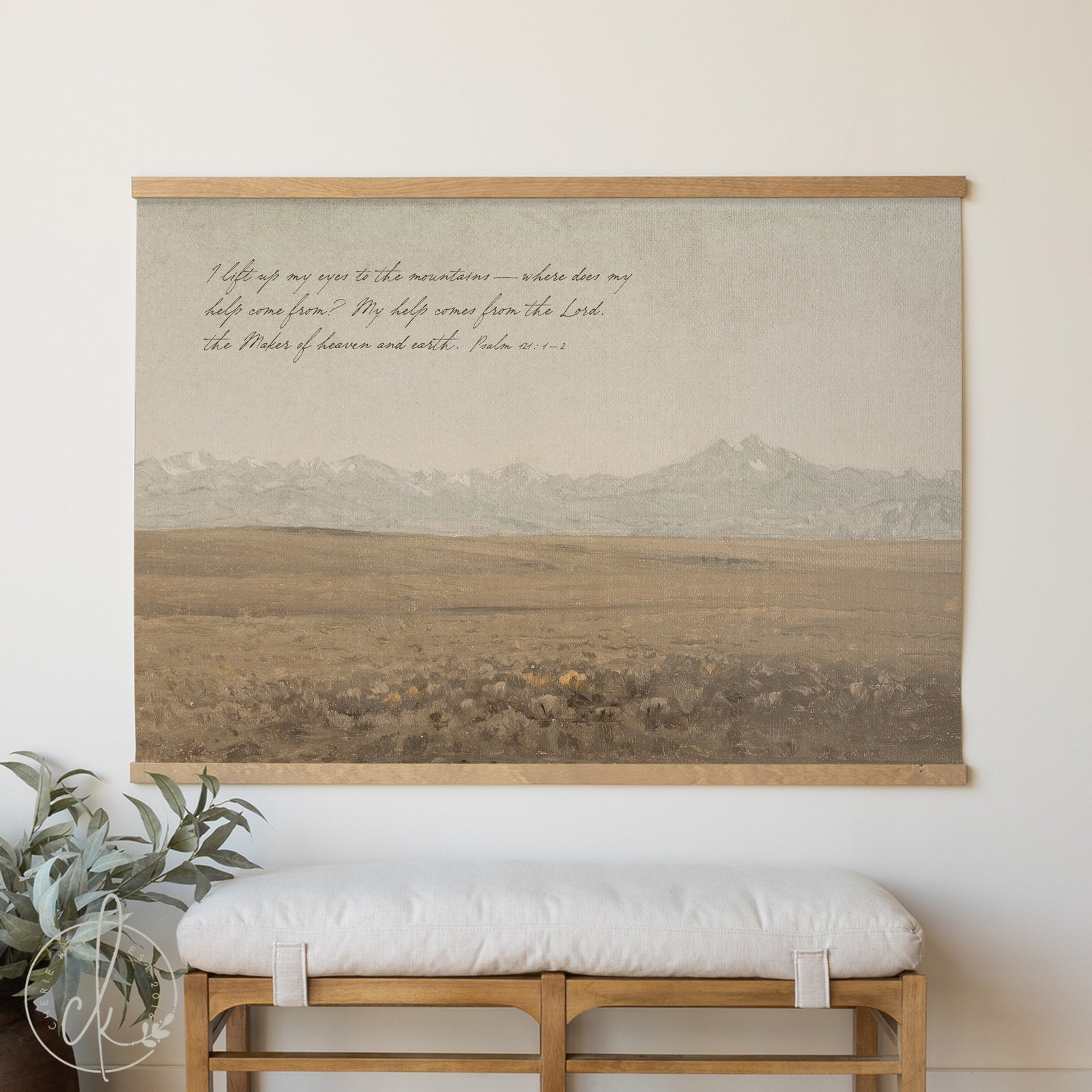 Wall art with landscape and text on a plain wall above a bench.