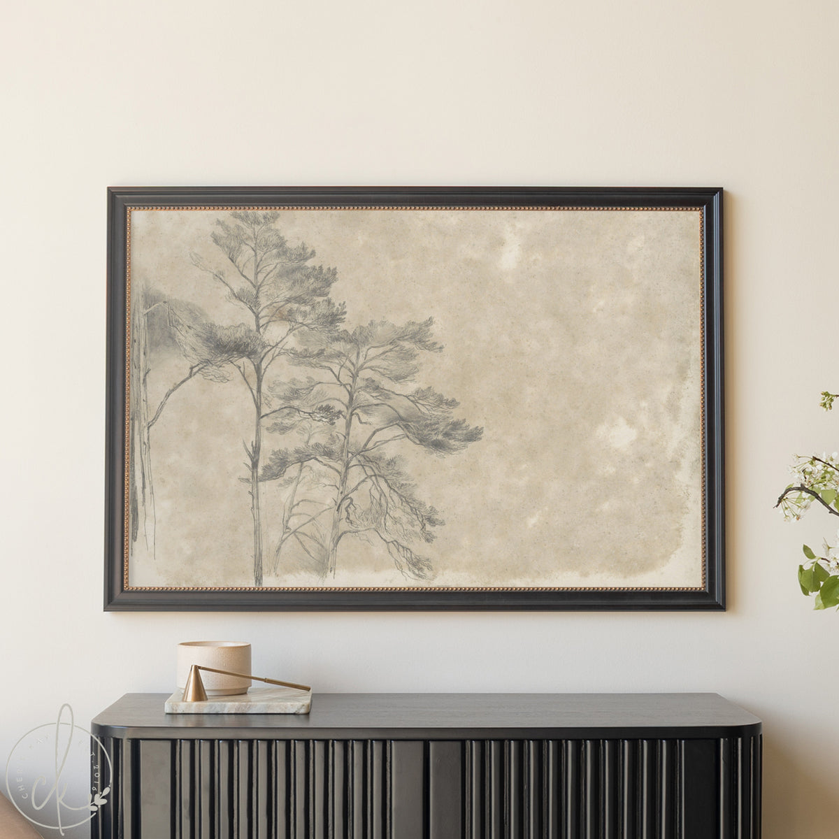 Framed artwork of trees on a textured beige background, displayed above a black console table.