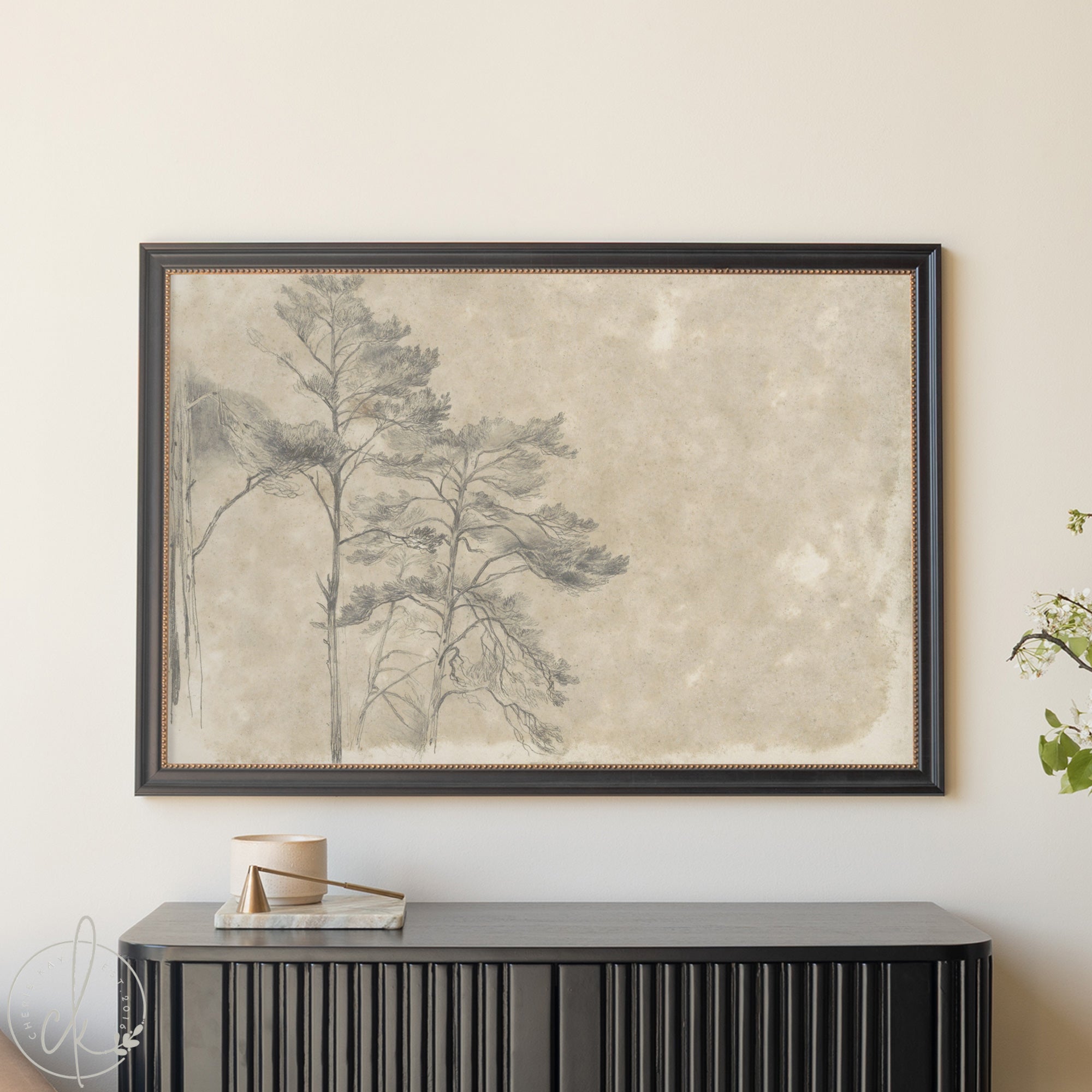 Framed artwork of trees on a textured beige background, displayed above a black console table.