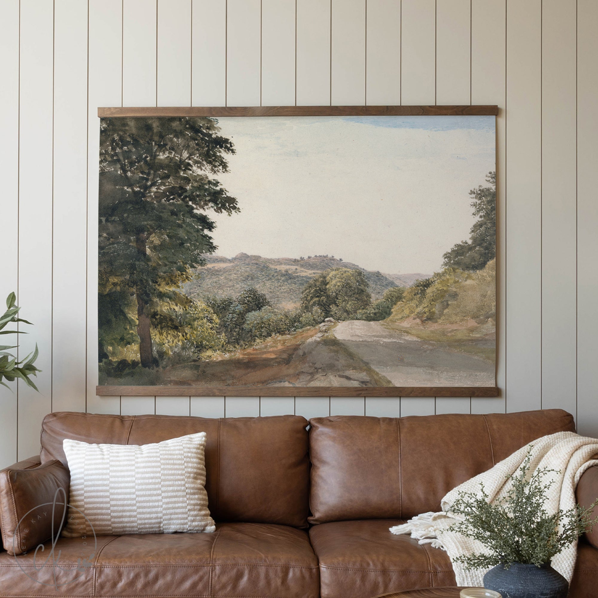 Brown leather sofa with a landscape painting on the wall in a living room setting.