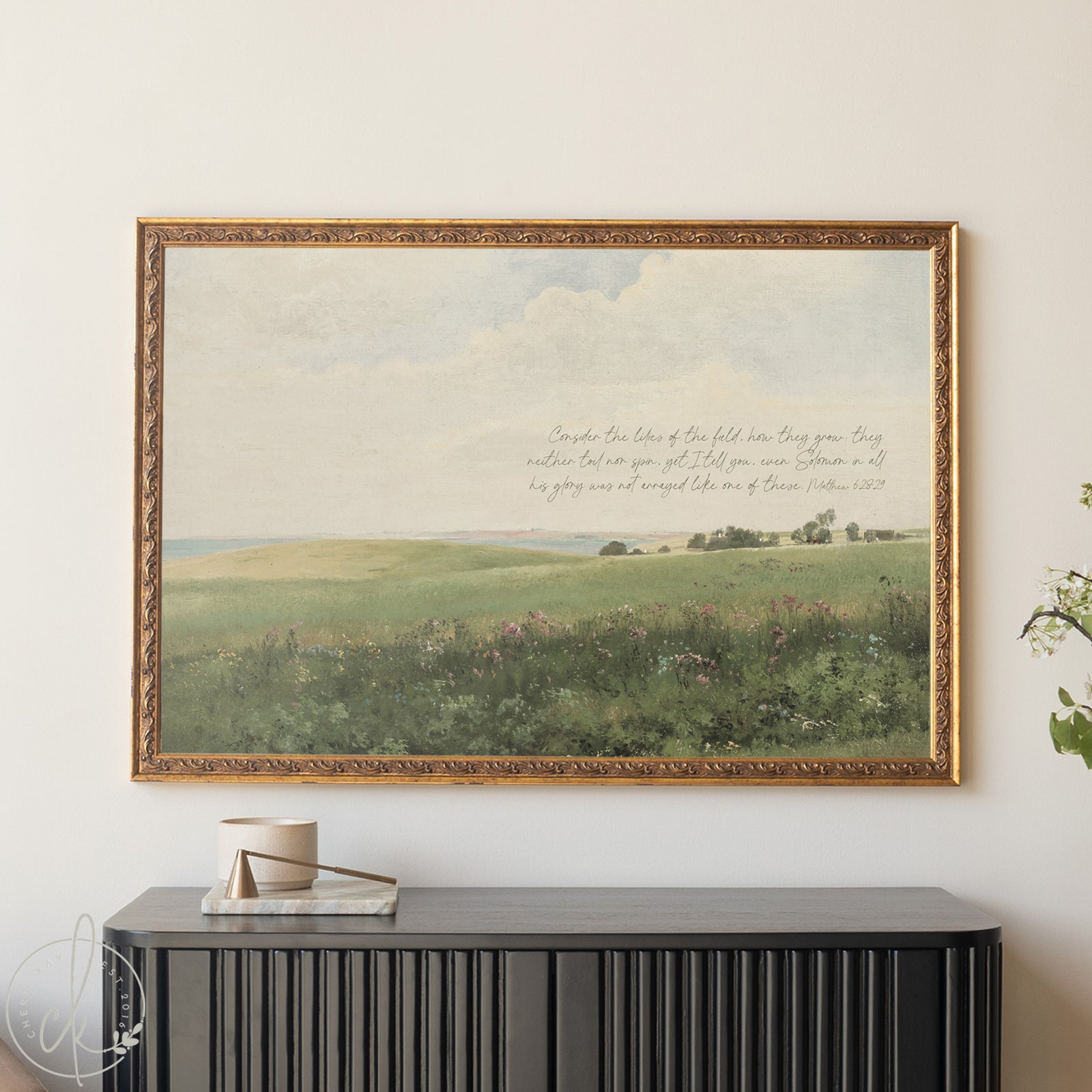Framed landscape painting with text above a black console table.