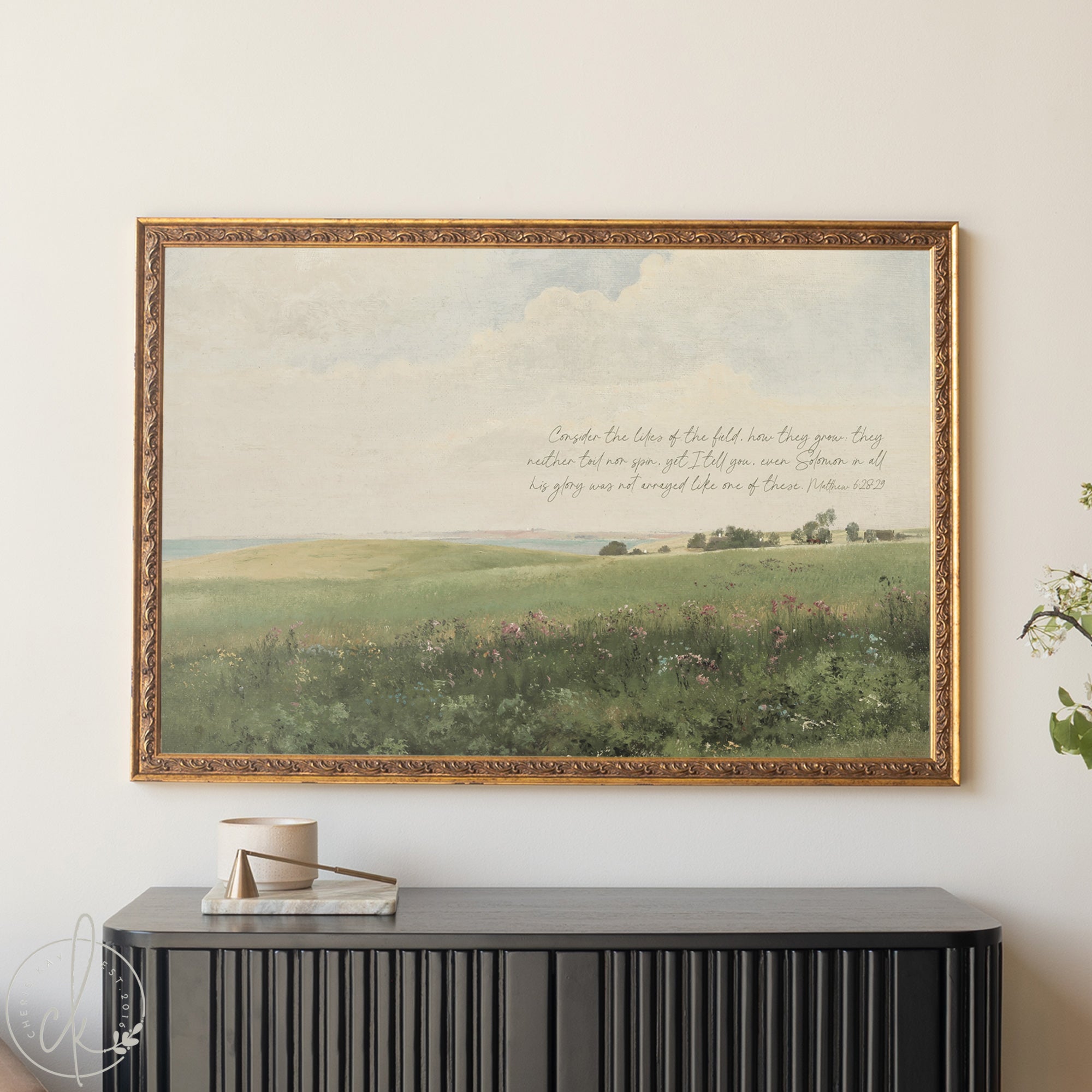 Framed landscape painting with text above a black console table.