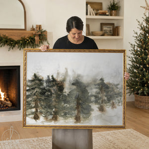 Framed Christmas wall art with watercolor pine trees in a winter forest scene.