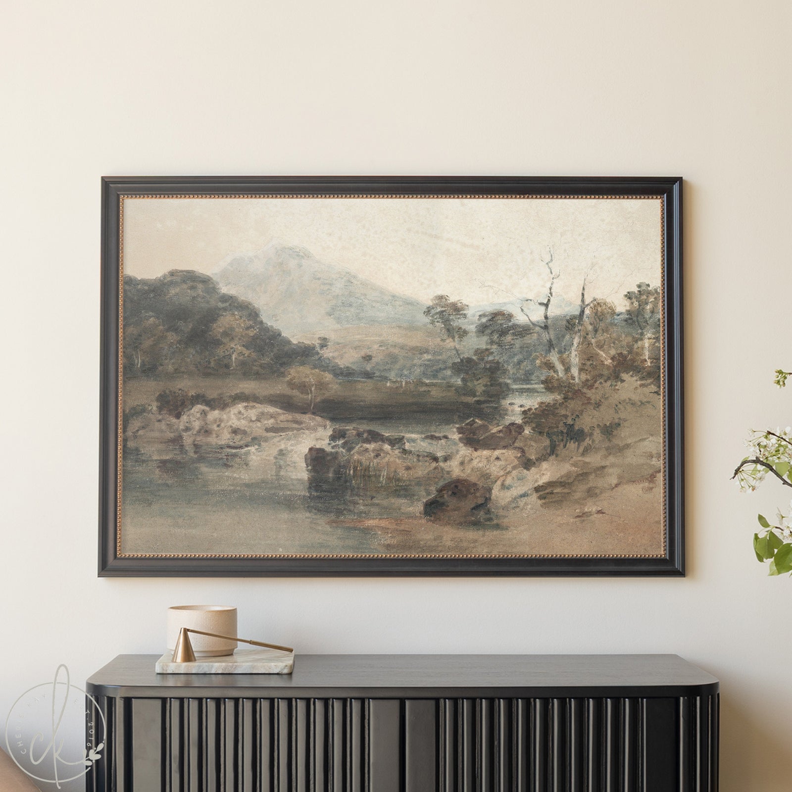 Framed landscape painting on a wall above a black console table.
