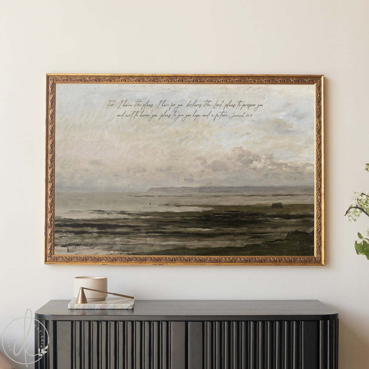 Framed landscape painting with text above a black console table.