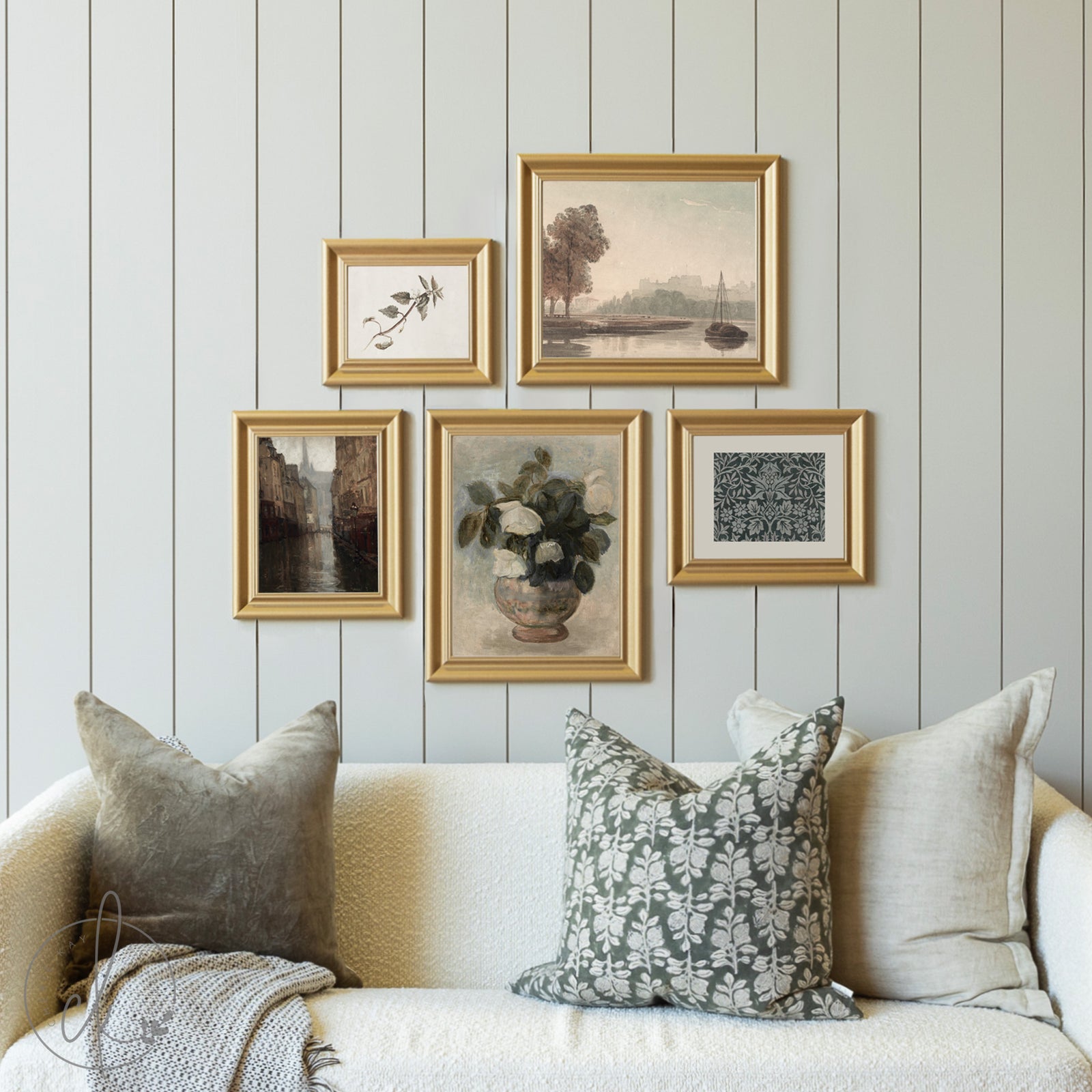 Decorative wall with framed art pieces above a sofa with patterned cushions.