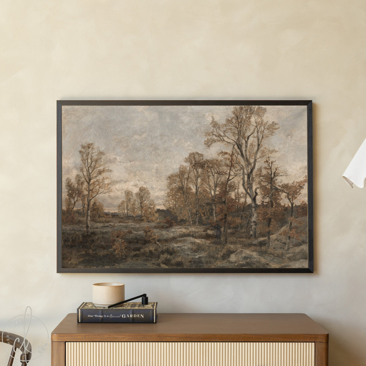 Framed landscape painting on a wall above a wooden cabinet.