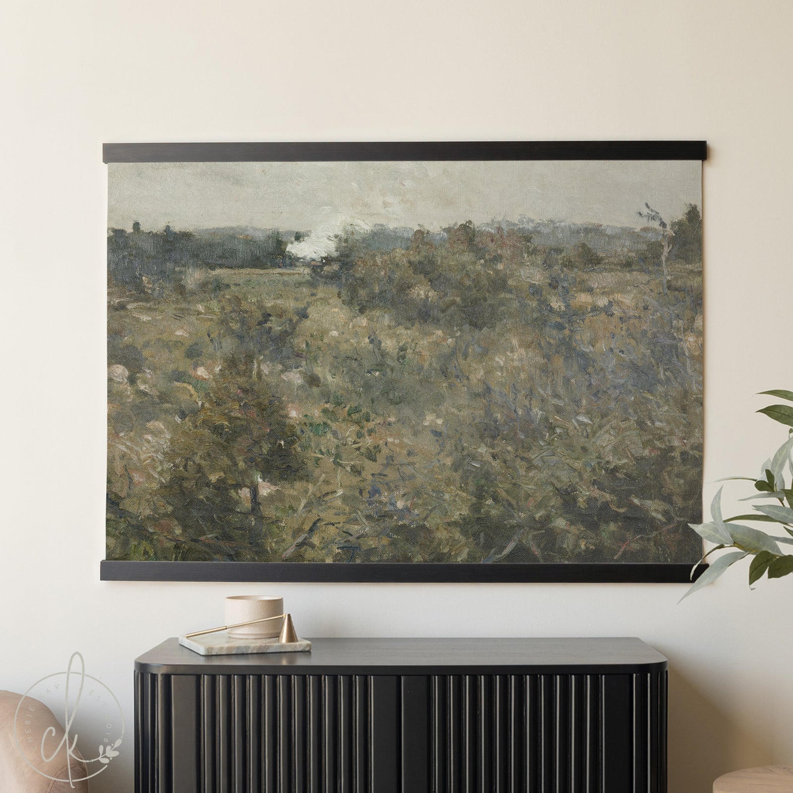 Framed landscape painting on a wall above a black cabinet.