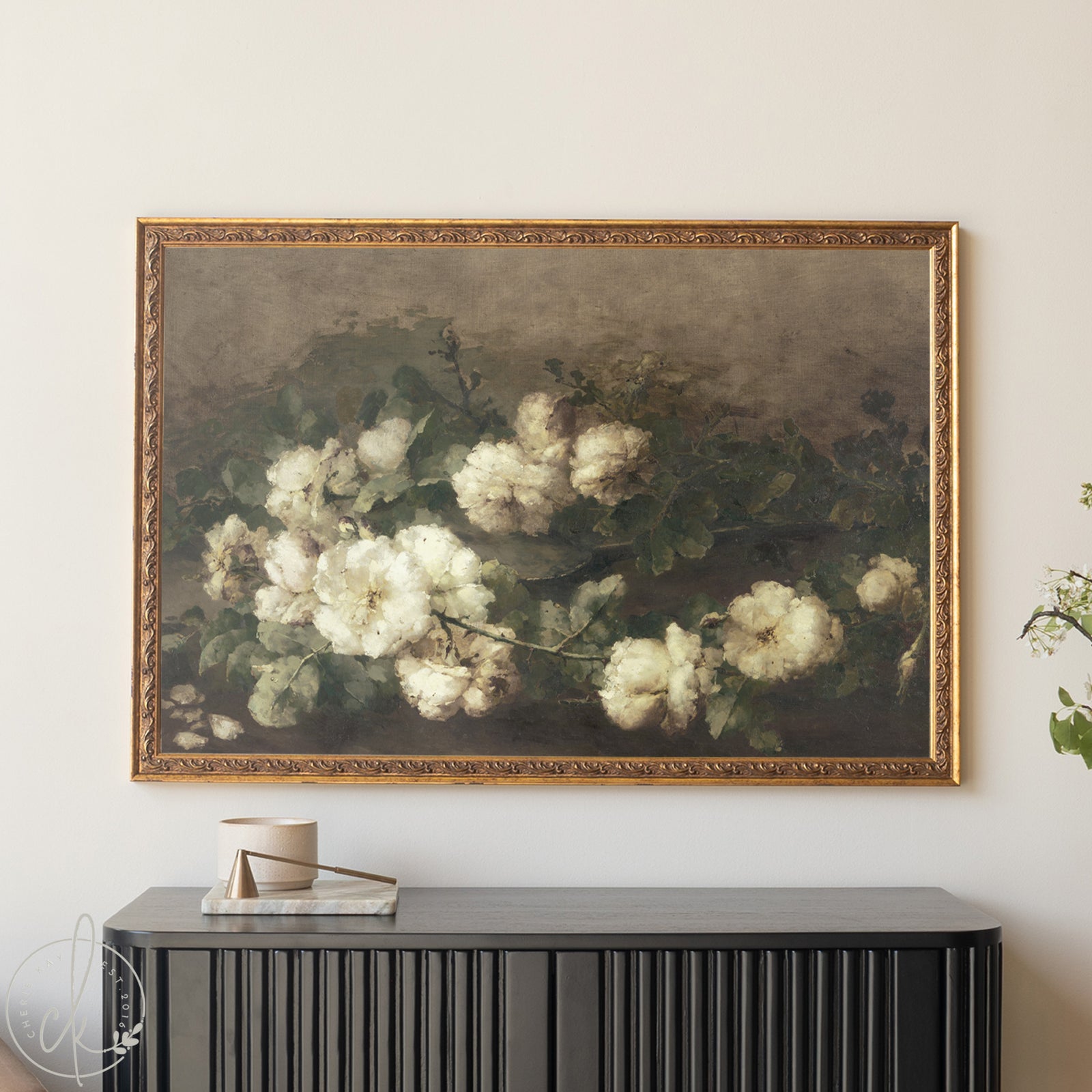 Framed painting of white flowers on a wall above a black console table.