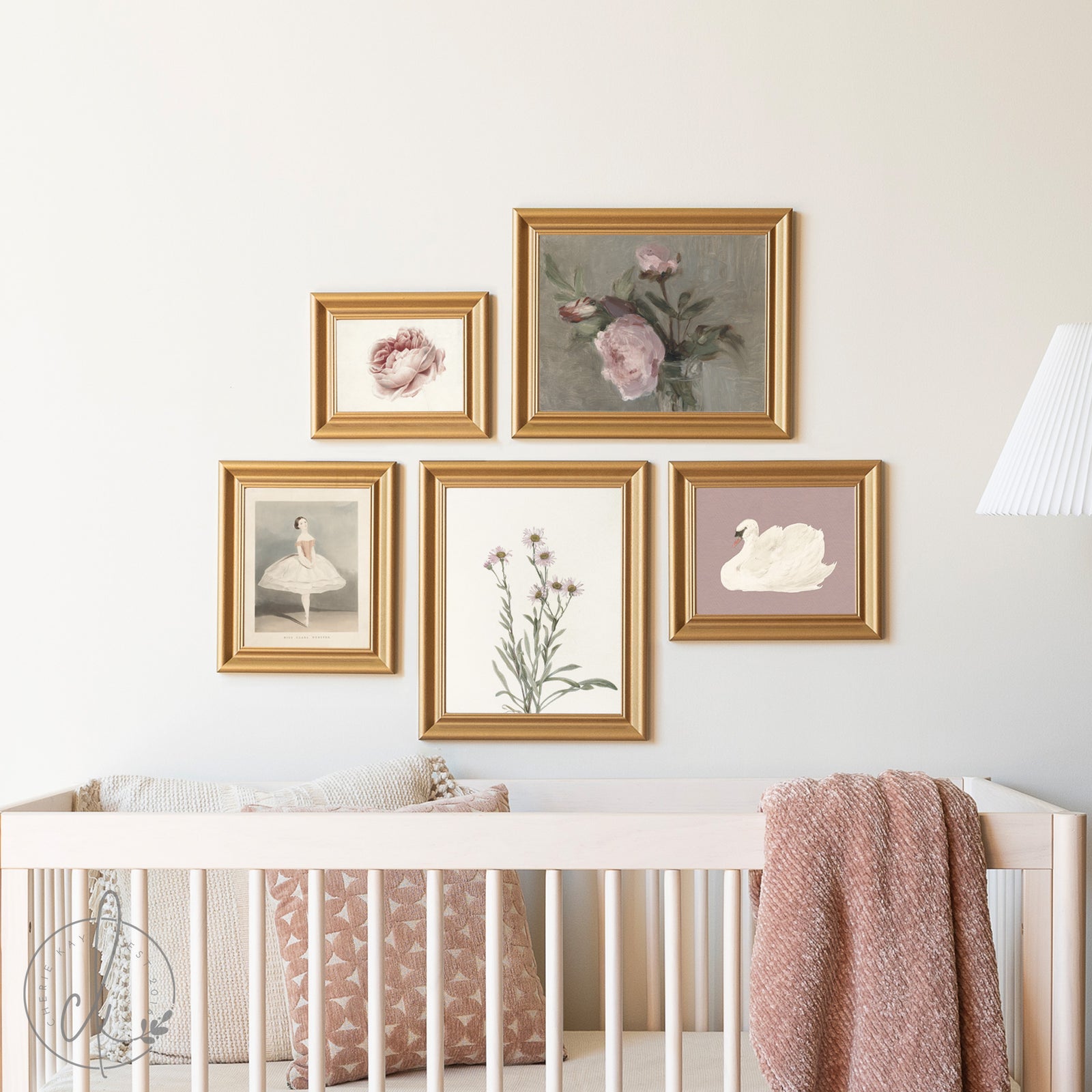 Framed artwork on a wall above a crib with pink and gold accents.
