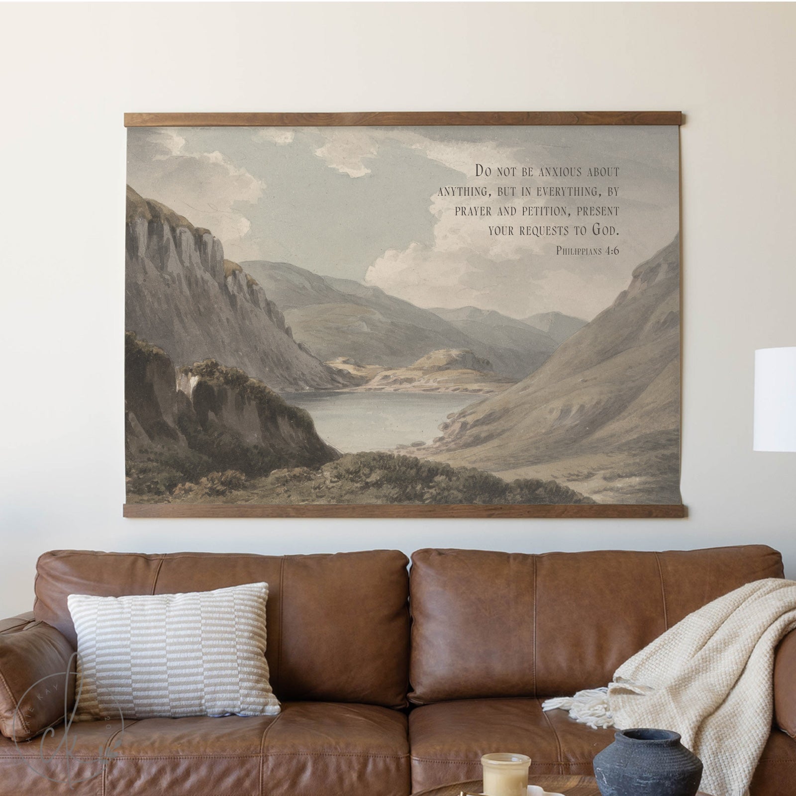 Large landscape painting above a brown leather sofa with a pillow and blanket.