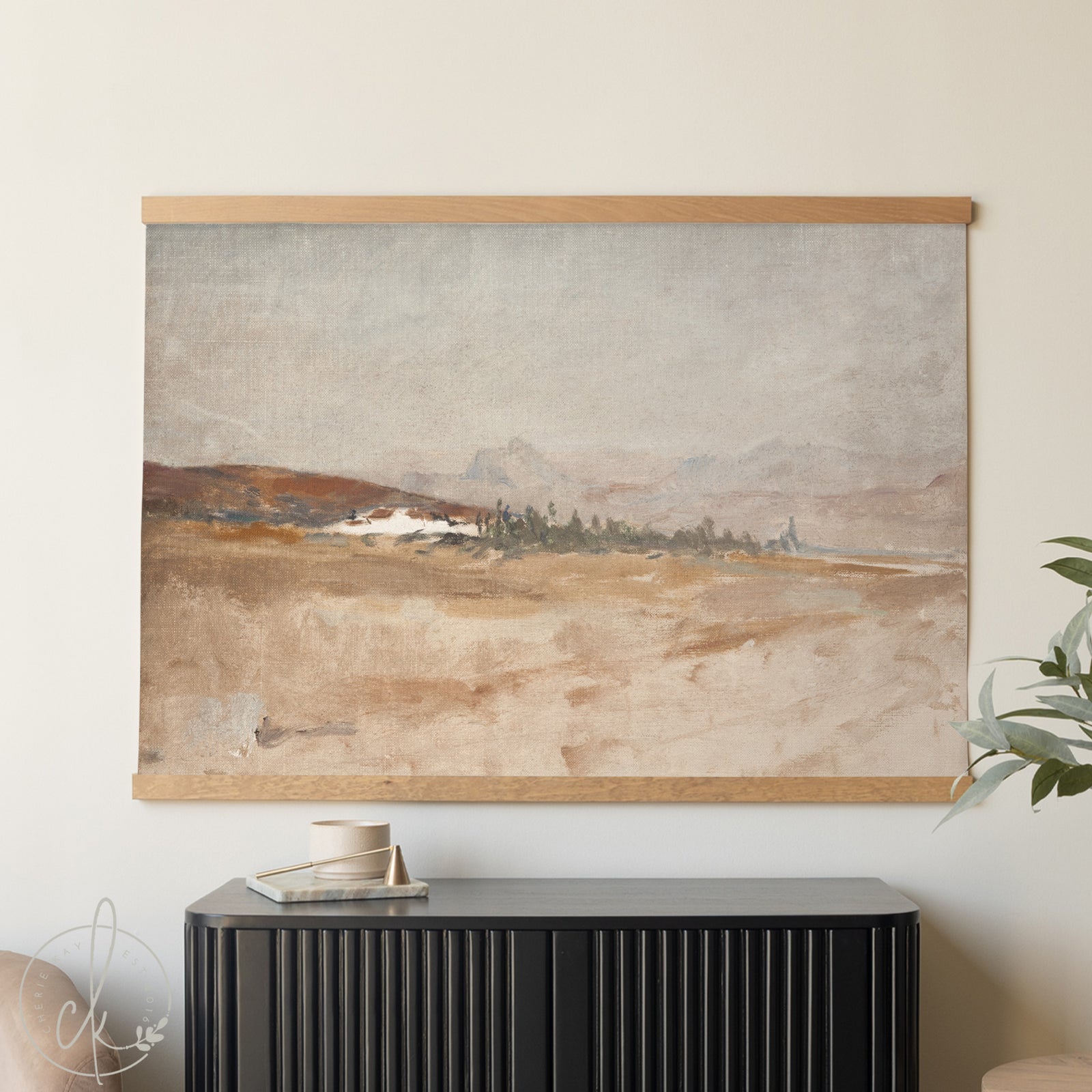 Framed landscape painting on a wall above a black cabinet.