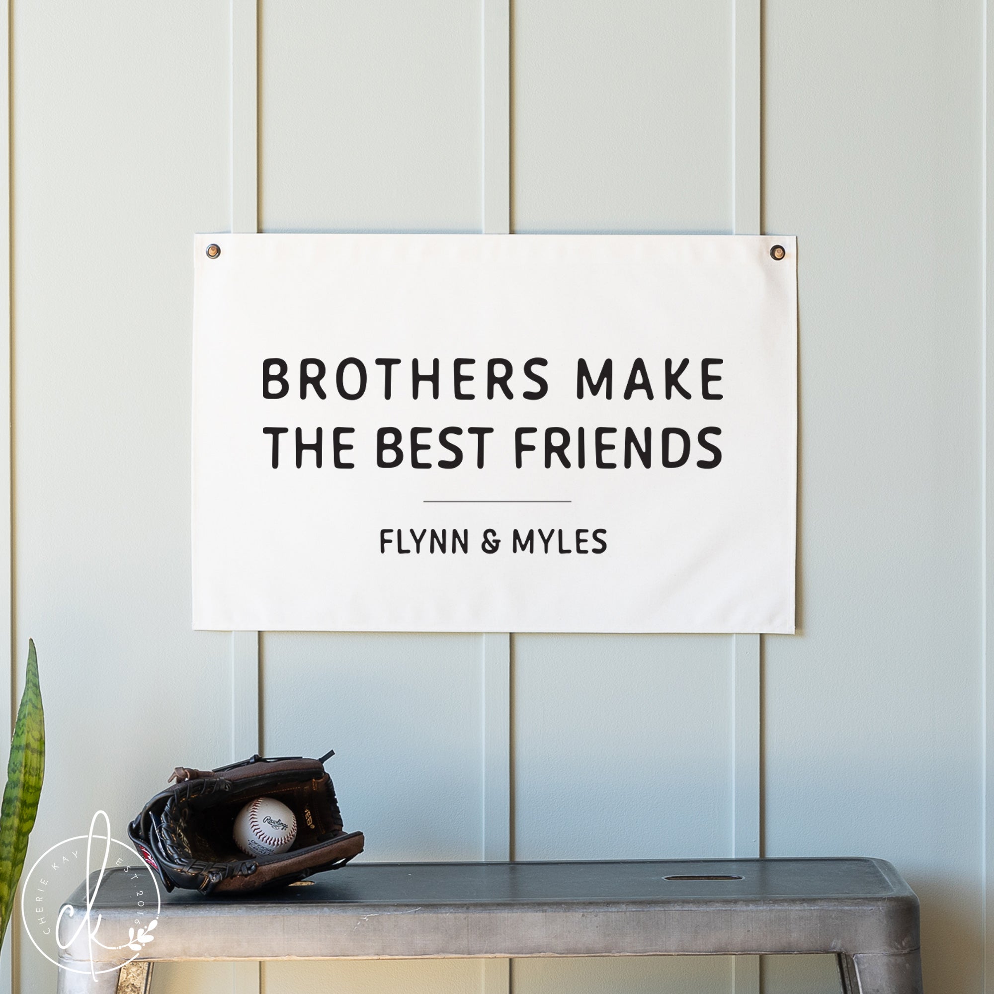 Decorative sign with 'Brothers Make the Best Friends' text on a wall with a glove and ball at the bottom.