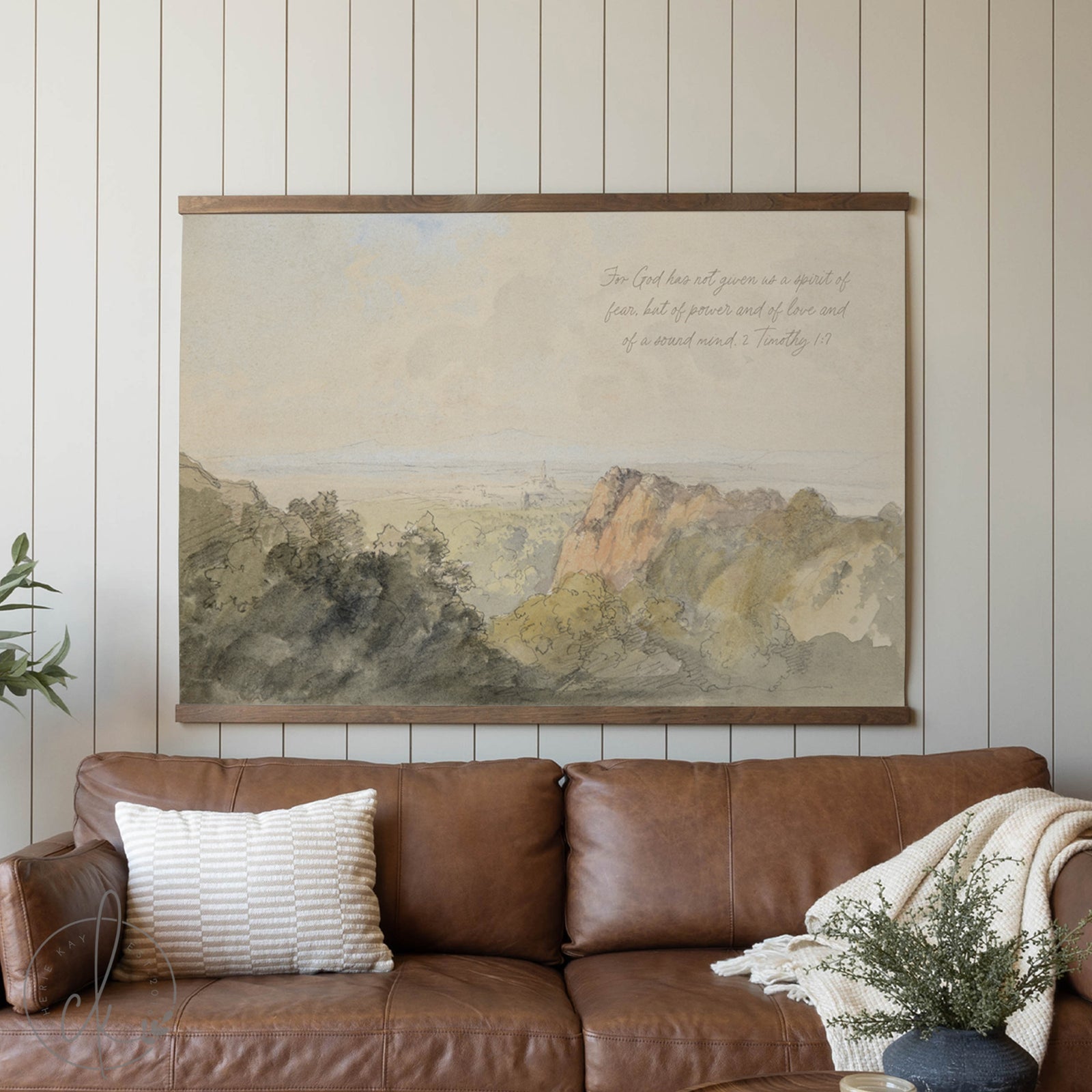 Brown leather sofa with a decorative pillow and blanket in a room with a large landscape painting on the wall.