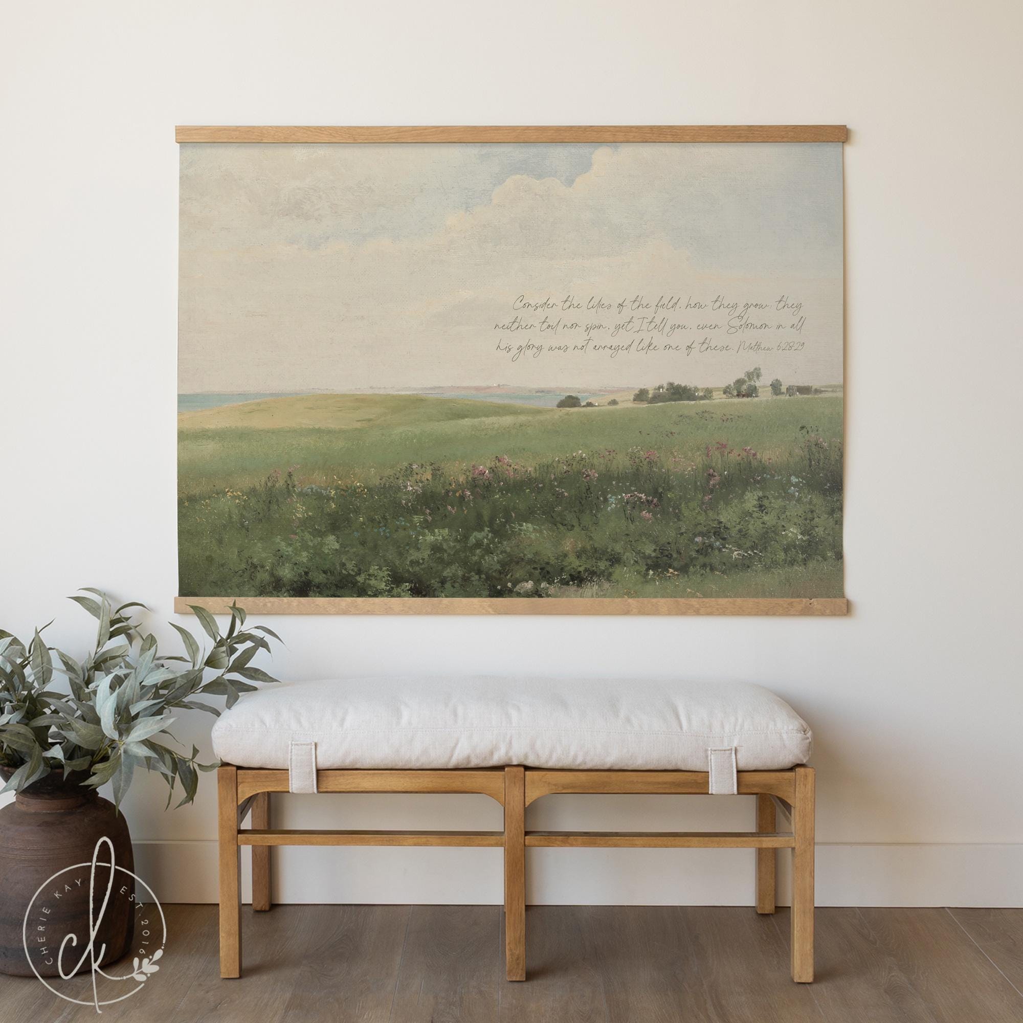 Canvas tapestry wall hanging with scripture displayed above wooden bench in modern home decor setting showing scale of large vintage landscape art