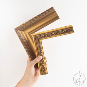 Hand holding two ornate gold wood frame corner samples side by side, showing different carved detail options for the antique horse print.
