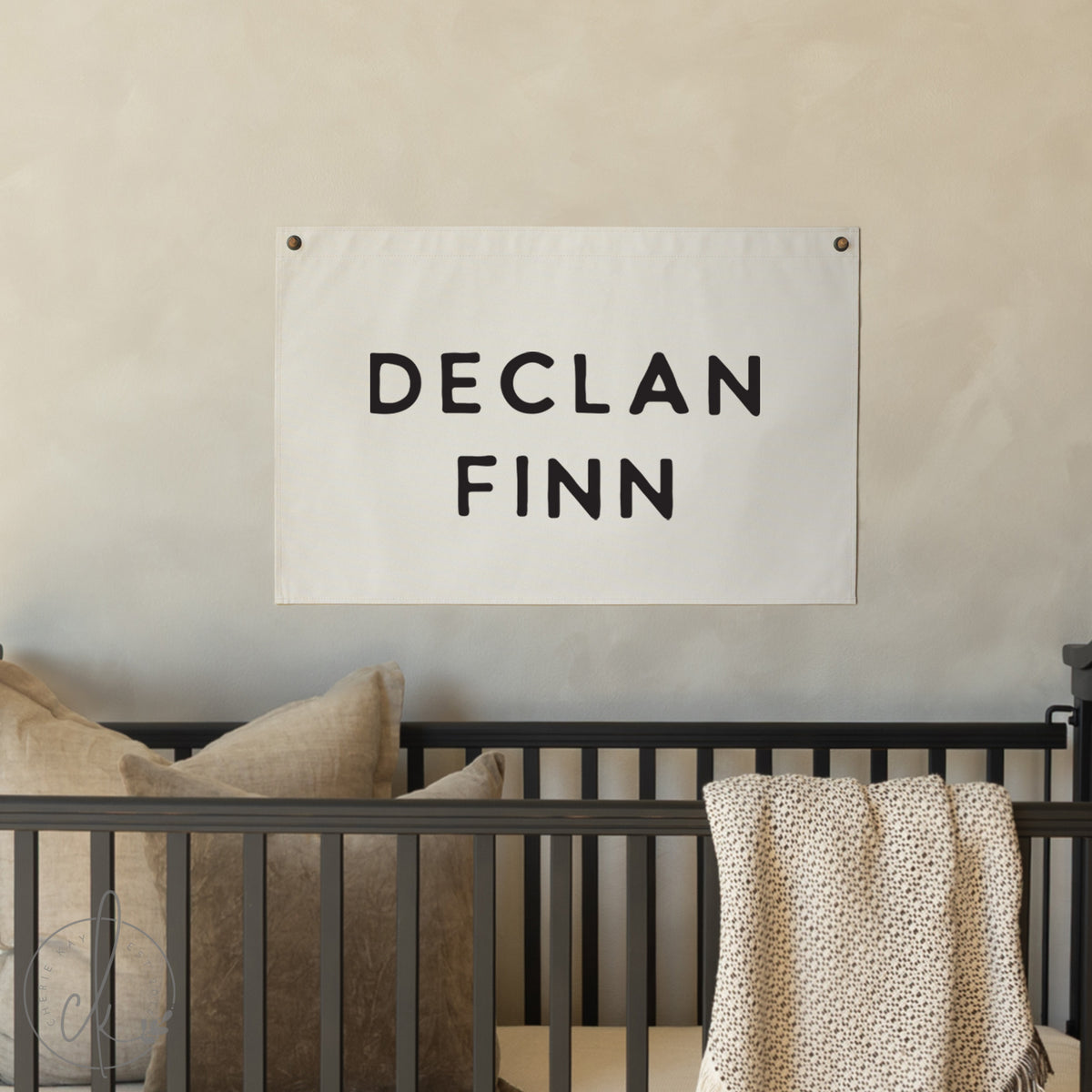 Nursery with a banner displaying &#39;DECLAN FINN&#39; above a crib.
