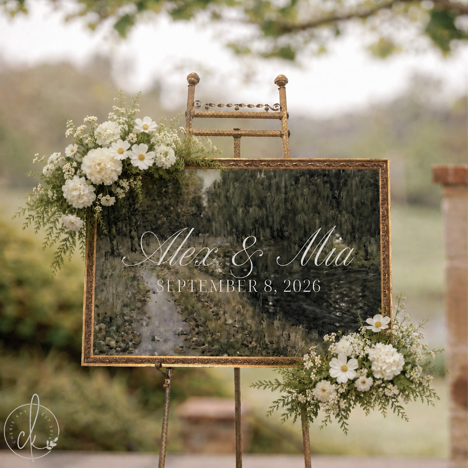 Wedding entrance sign with green Impressionist landscape, gold frame, names and date, on a gold easel outdoors