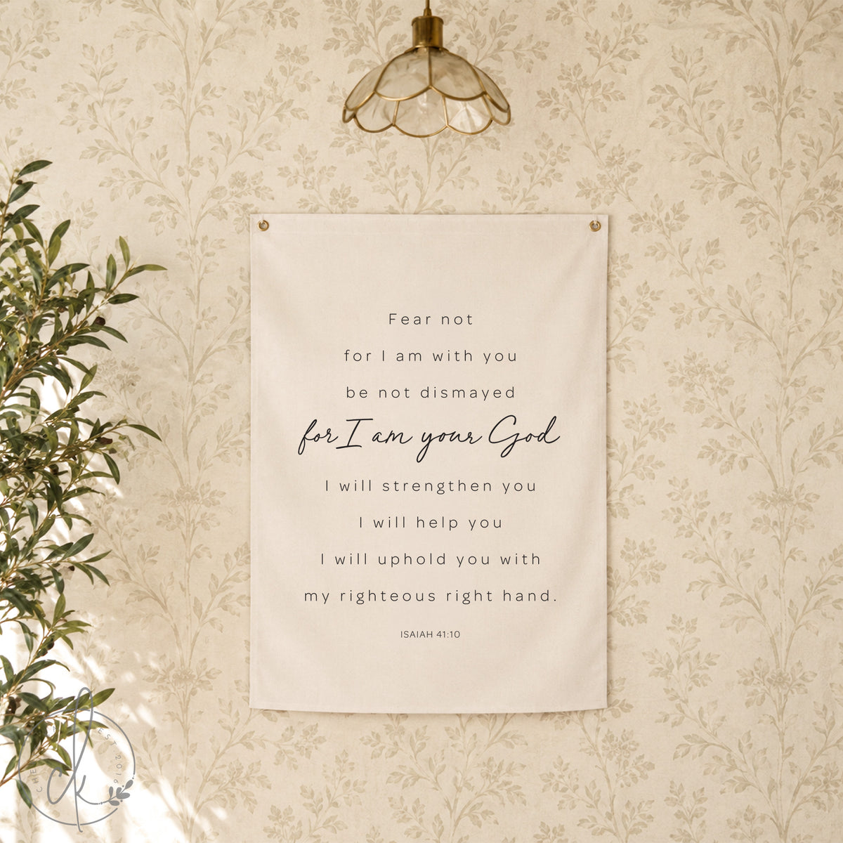 A white canvas wall tapestry with black text that reads "Fear not for I am with you be not dismayed for I am your God I will strengthen you I will help you I will uphold you with my righteous right hand. Isaiah 41:10". 