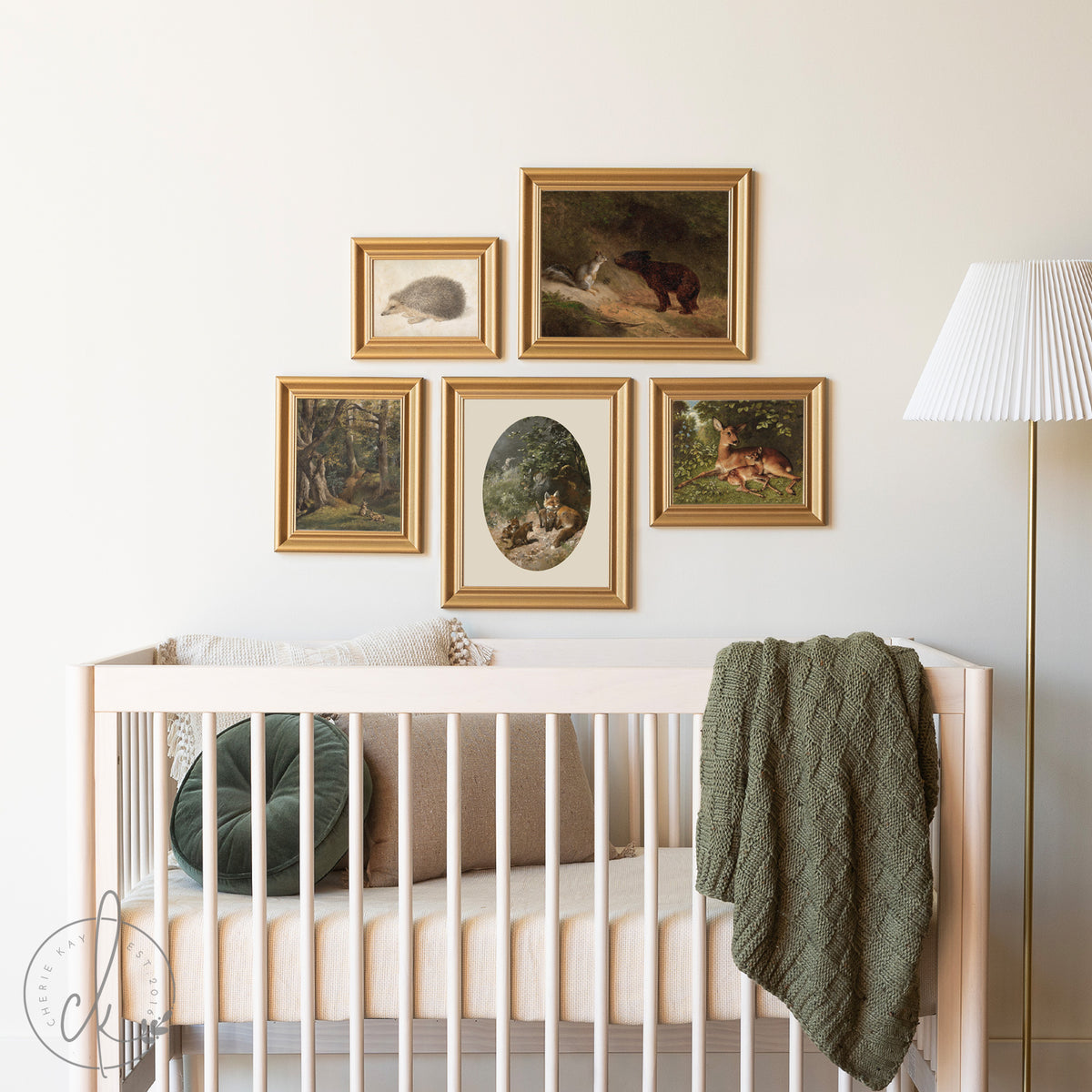 Nursery with a wooden crib and a gold-framed gallery wall featuring vintage-style woodland animal prints