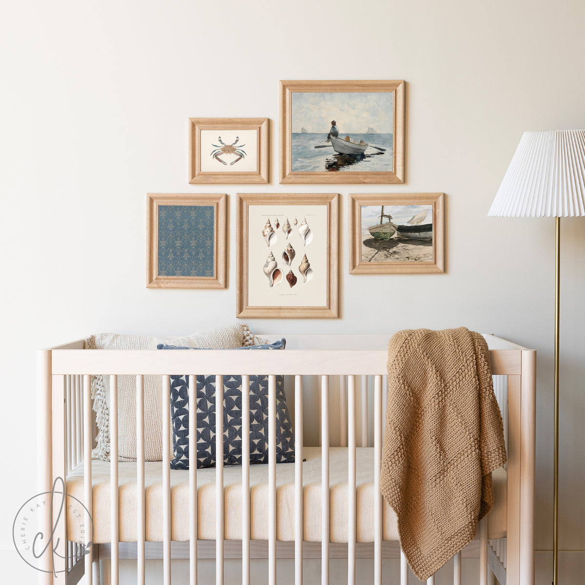 Vintage coastal art collage featuring framed ocean-themed prints with seashells, boats, and crabs, styled as wall decor above a neutral-colored crib in a beach-themed nursery. Perfect for coastal or beach house decor.