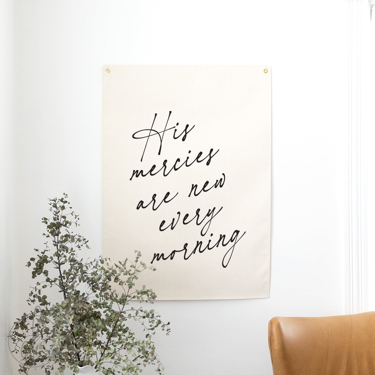 Poster with &#39;His mercies are new every morning&#39; text on a wall with a plant and chair.