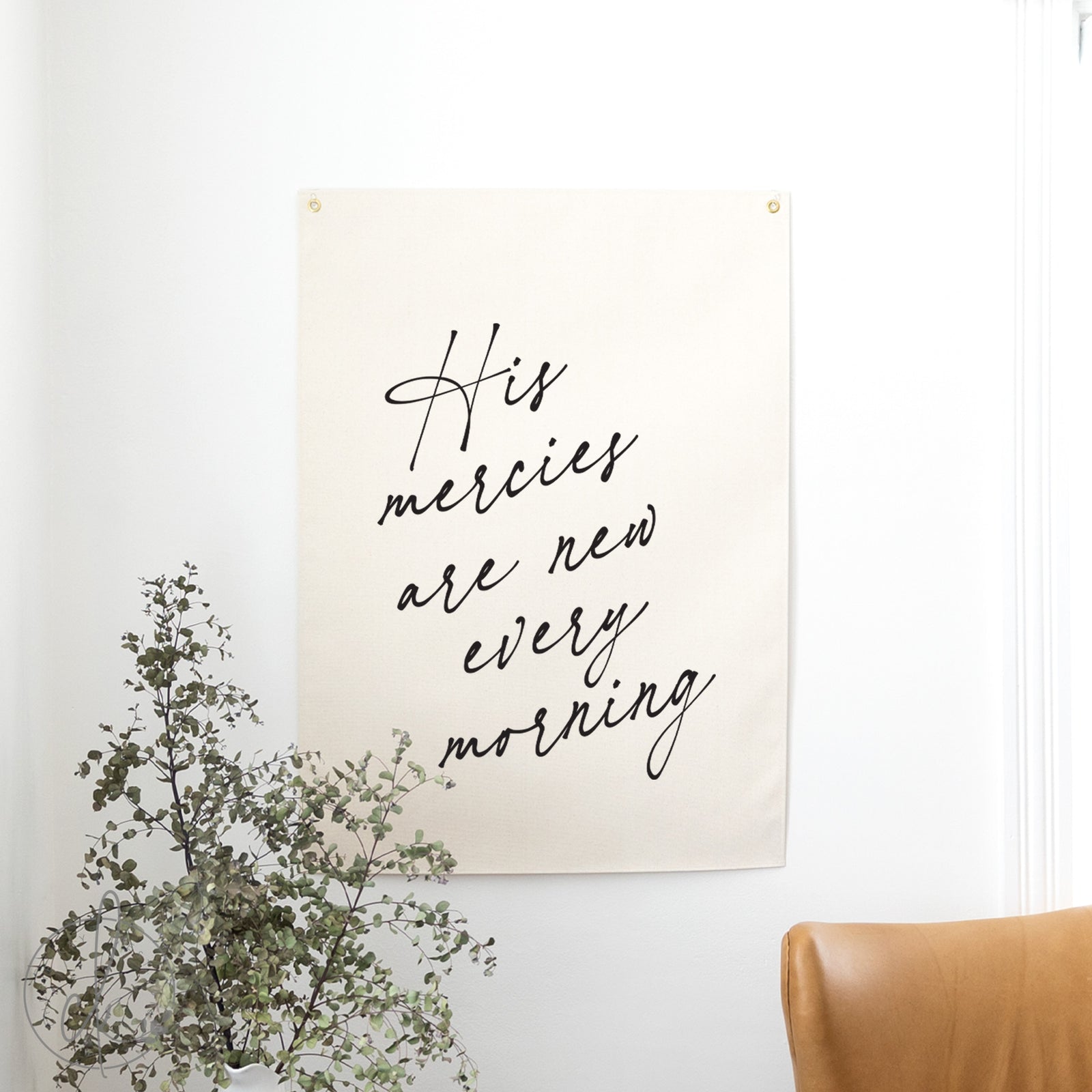Poster with 'His mercies are new every morning' text on a wall with a plant and chair.