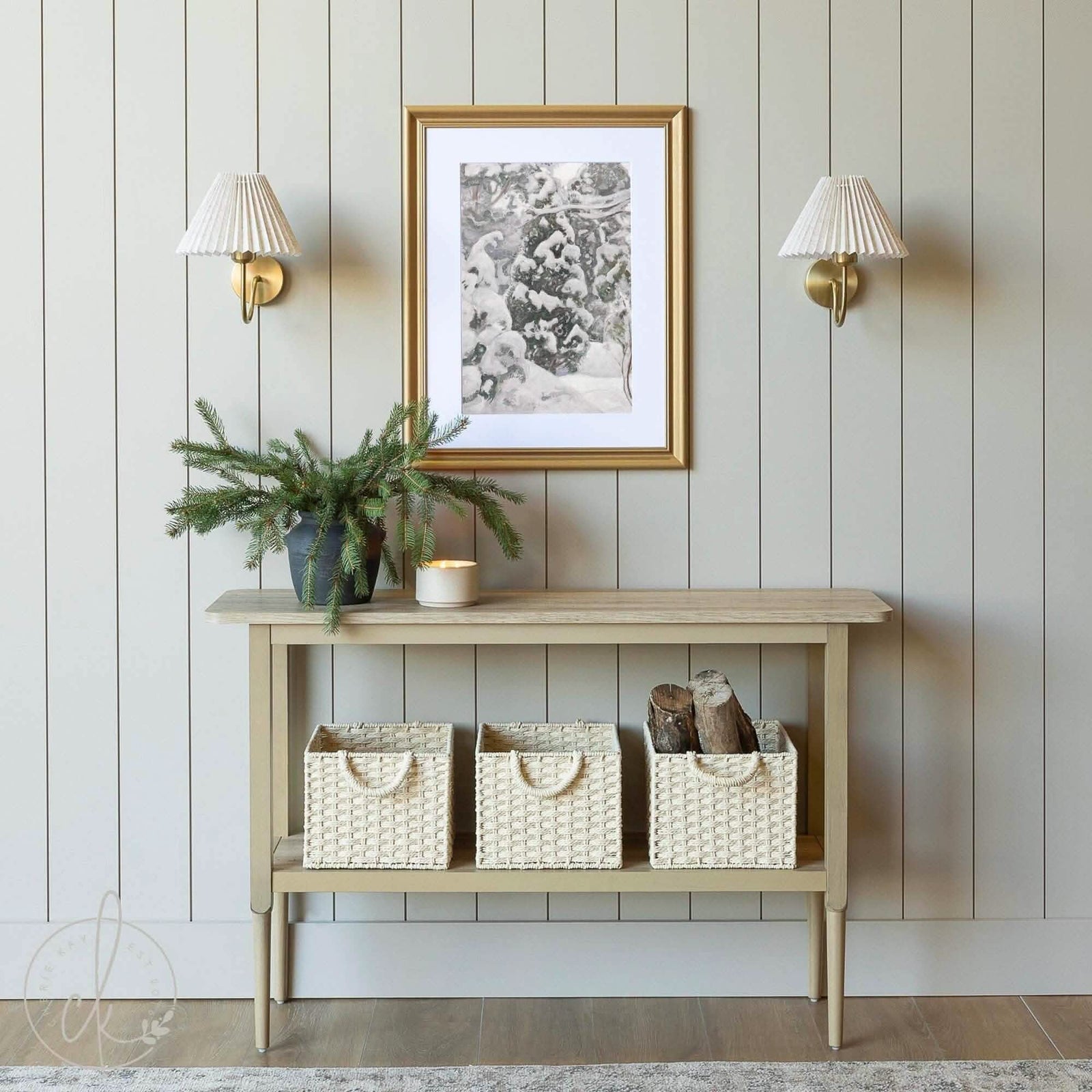 Rustic entryway with framed winter art of snowy pine trees, a wooden console, and woven baskets for cozy décor.