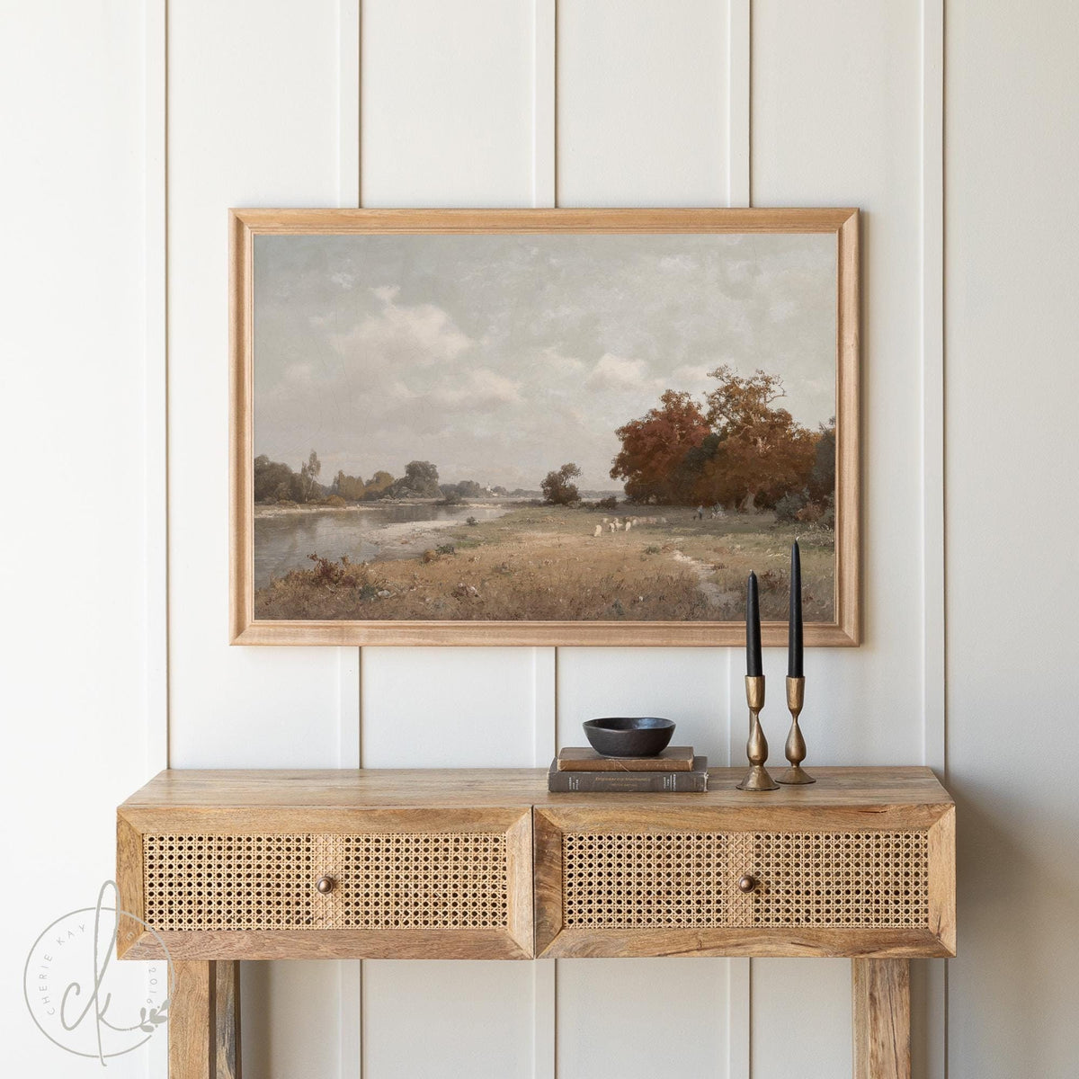 Framed fall landscape art above a wooden console table with brass candle holders, creating a cozy, rustic decor setting.