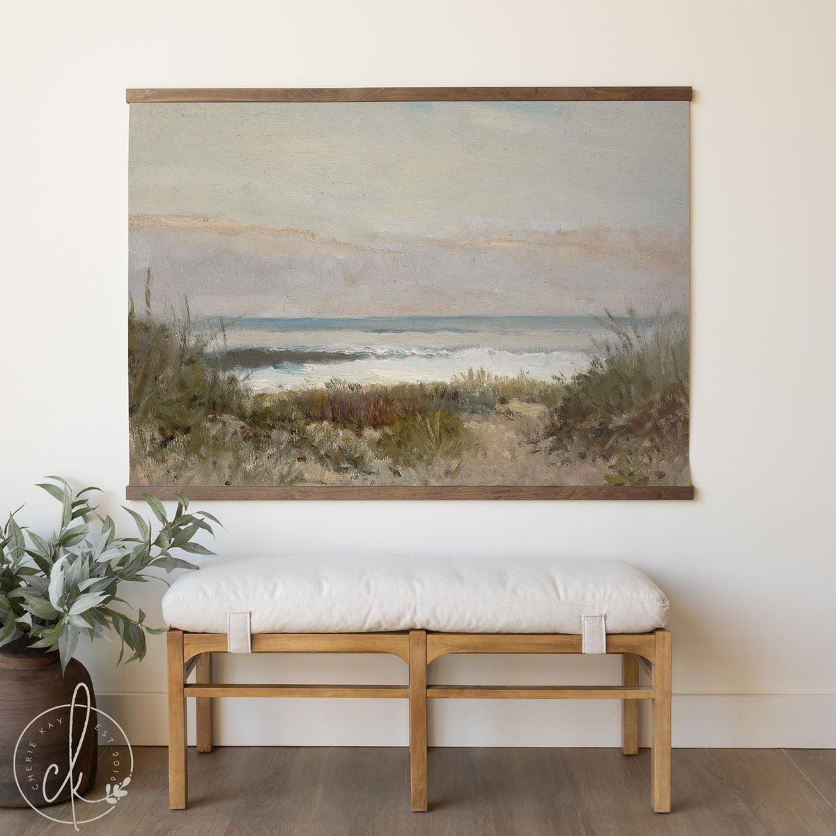 Large coastal tapestry featuring a vintage-style beach landscape with ocean waves, hung above a wooden bench in a neutral, minimalist room.