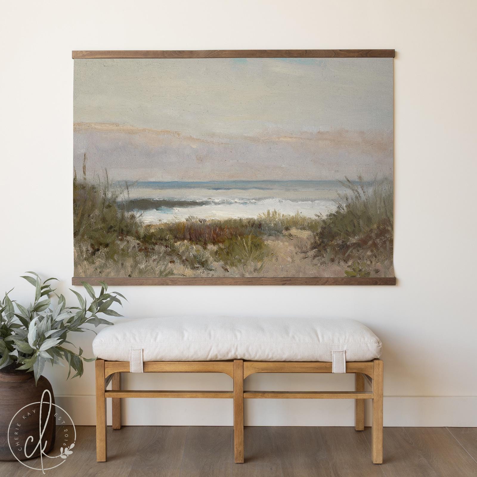 Large coastal tapestry featuring a vintage-style beach landscape with ocean waves, hung above a wooden bench in a neutral, minimalist room.