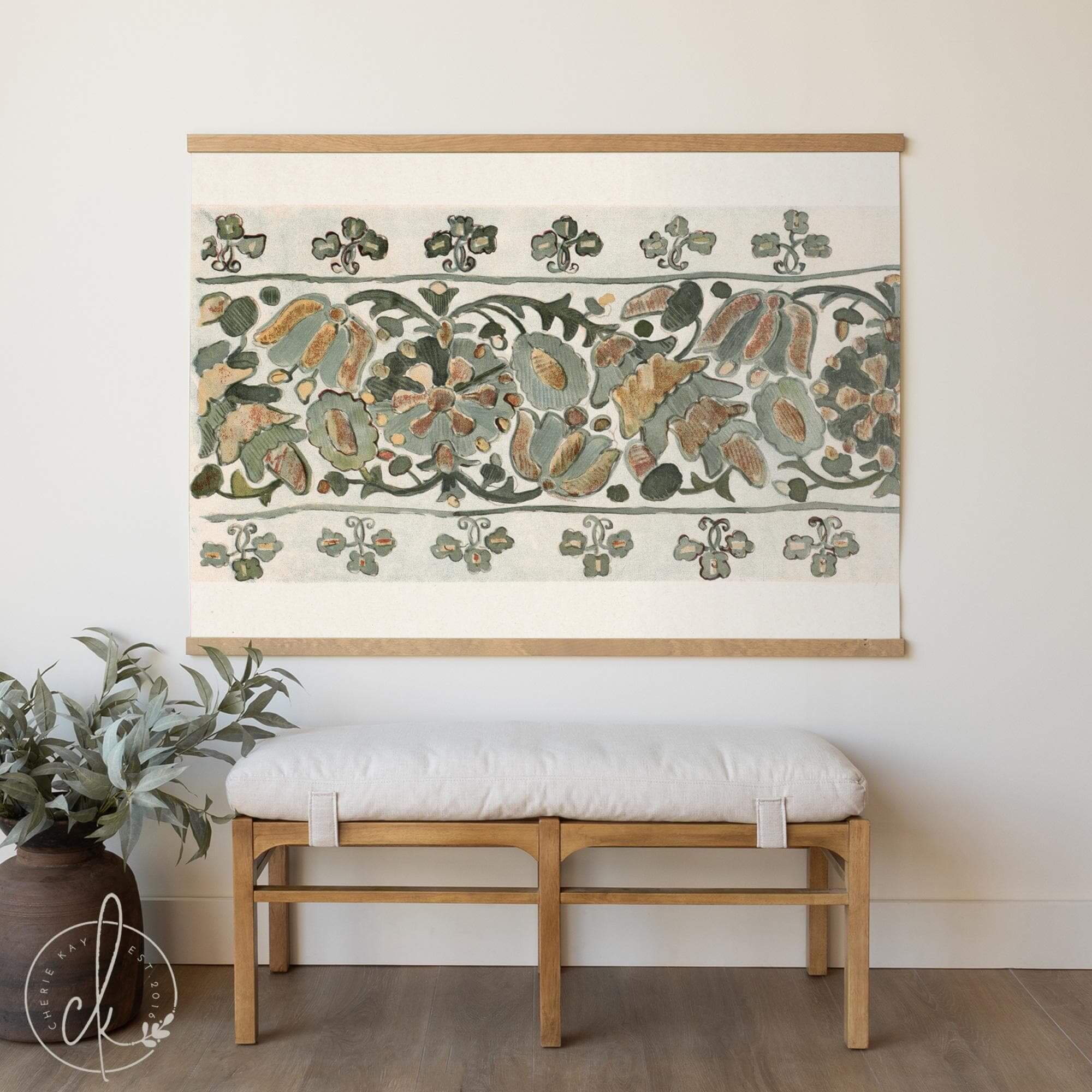 Vintage floral tapestry wall hanging featuring botanical textile print in green and rust tones, styled above a bench in a neutral entryway with wood floors and greenery.