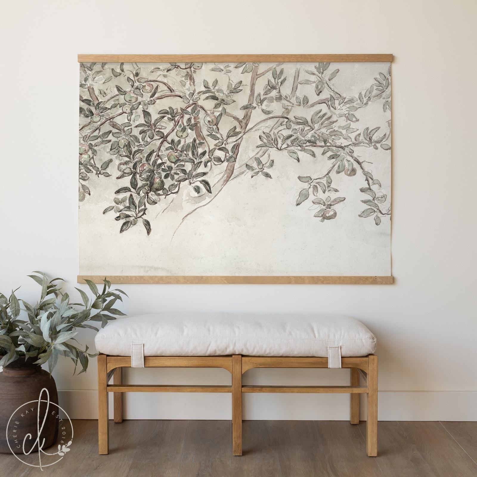 Neutral olive branch tapestry wall art—oversized botanical canvas hanging with sage-green leaves and minimalist oak bars, styled above a wooden bench.