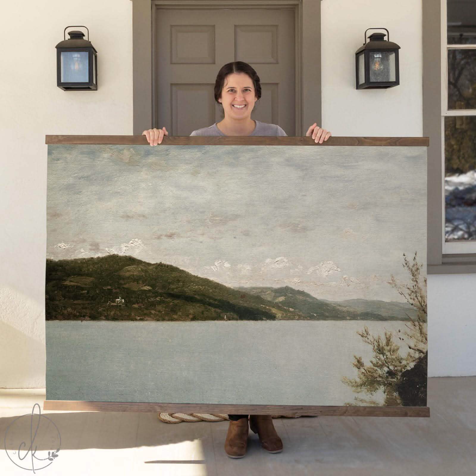 Extra-large art on a canvas tapestry featuring a serene, vintage-inspired lake landscape with rolling hills and lush trees, displayed in a cozy living space.