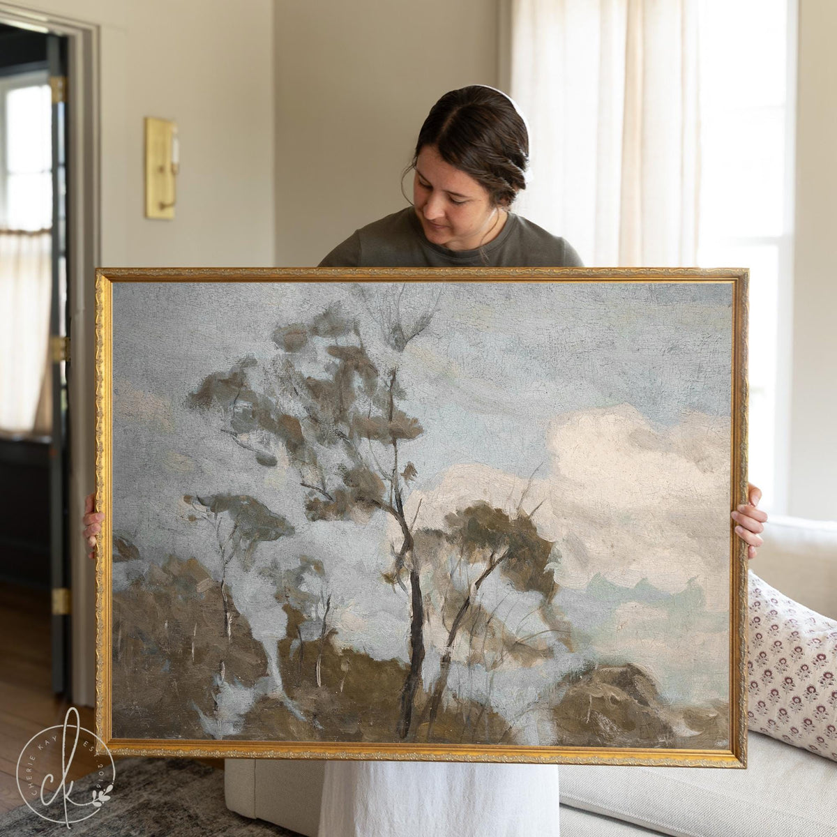 Framed landscape art featuring a moody tree scene with a grey sky, in an ornate gold frame, ready to hang.