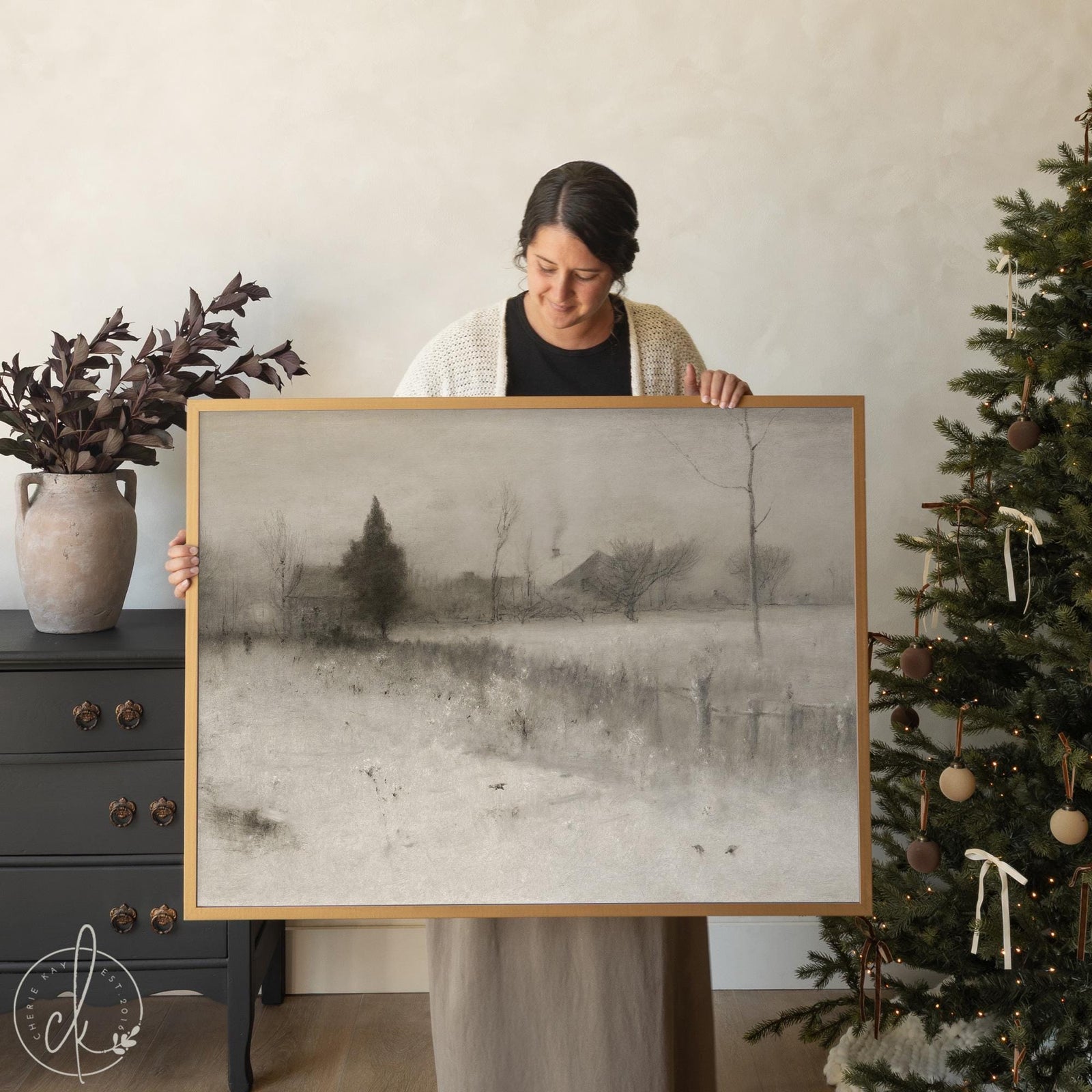 Framed snowy landscape painting in neutral tones, large winter wall art with trees and farmhouse.