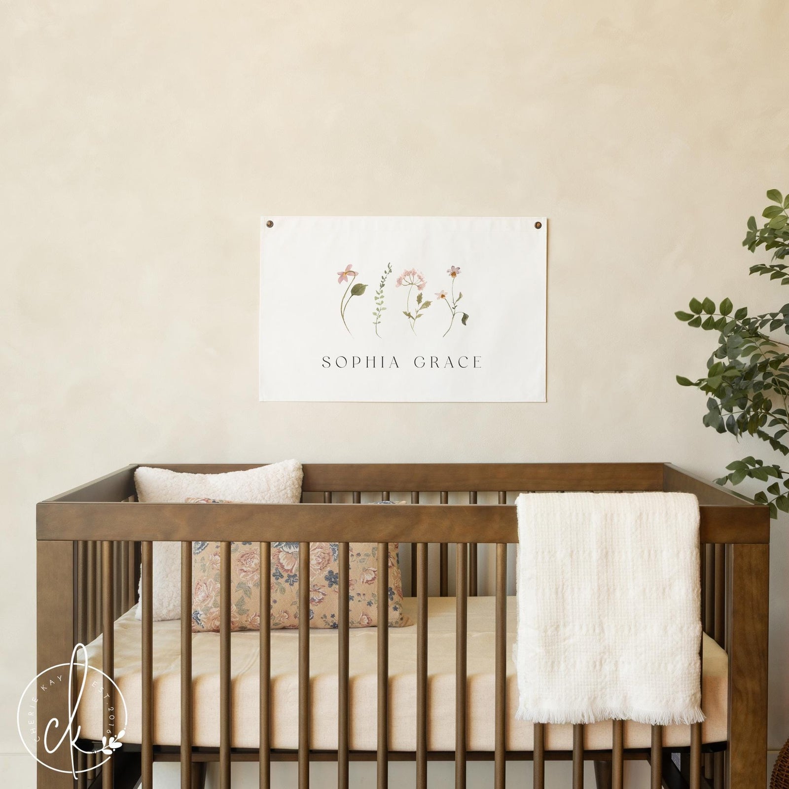 Personalized floral nursery decor with a girl baby name printed on canvas wall hanging.
