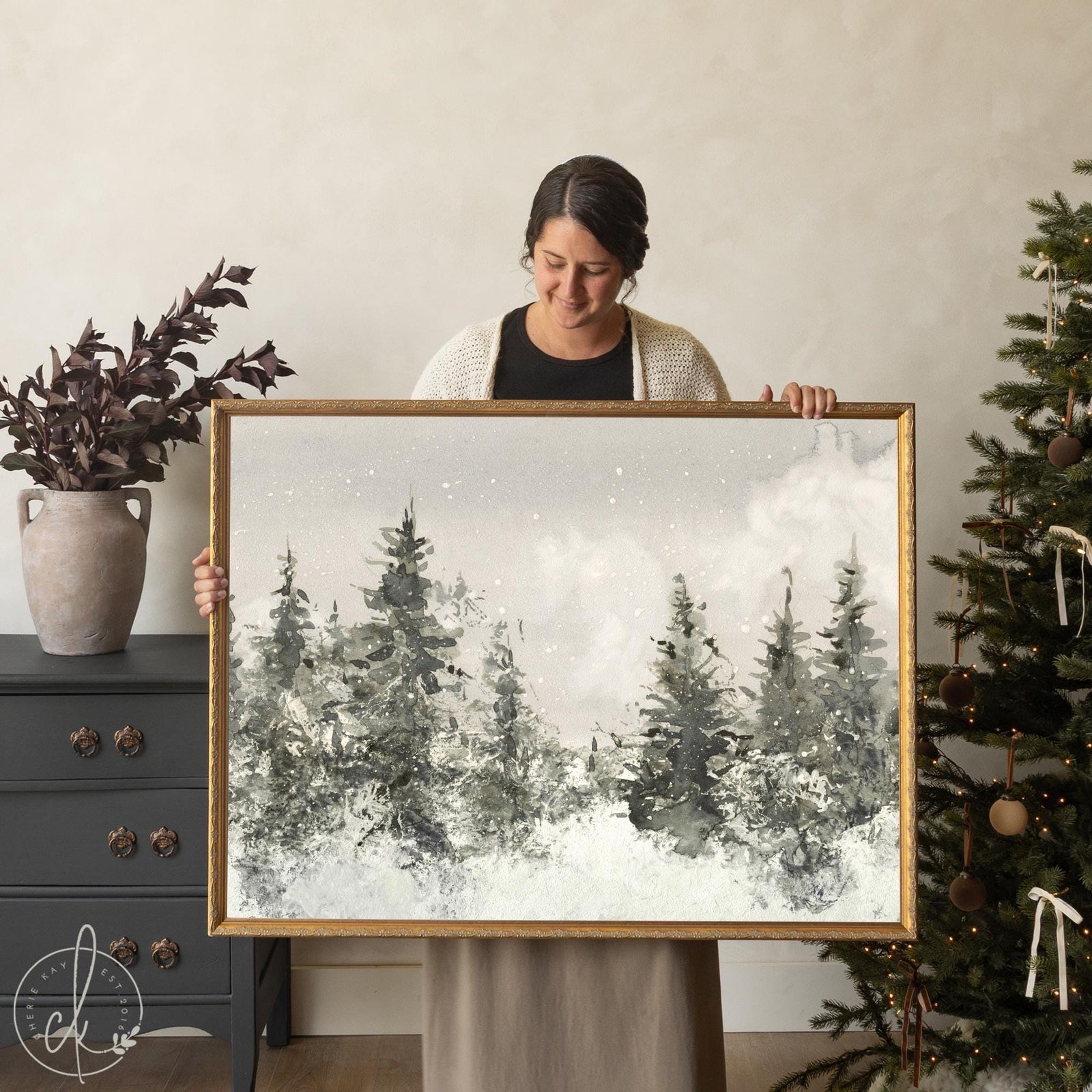 Framed winter landscape painting with snowy forest scene and neutral Christmas wall decor style.